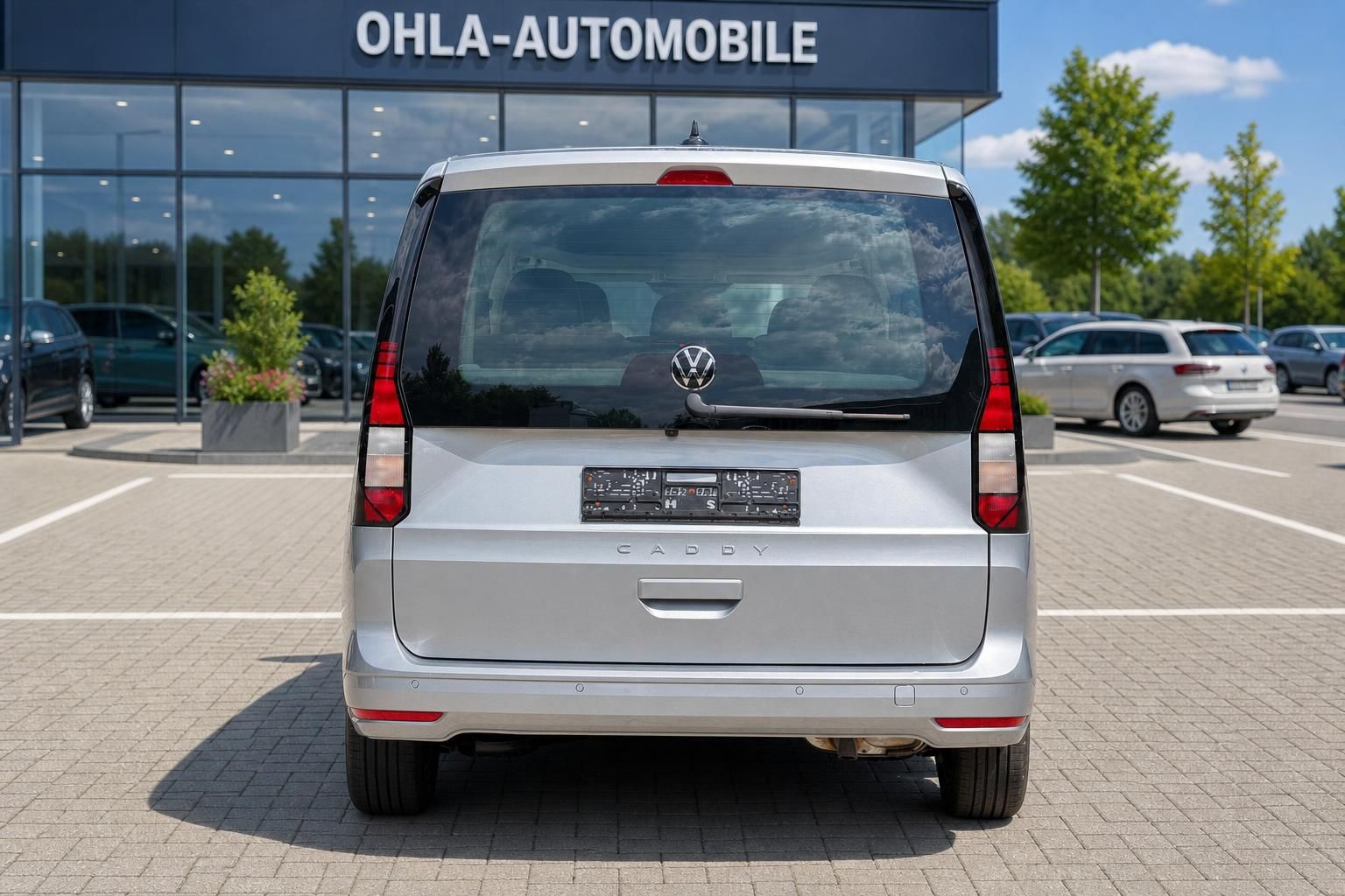 VW Caddy silber Heckansicht mit Ohla-Automobile im Hintergrund