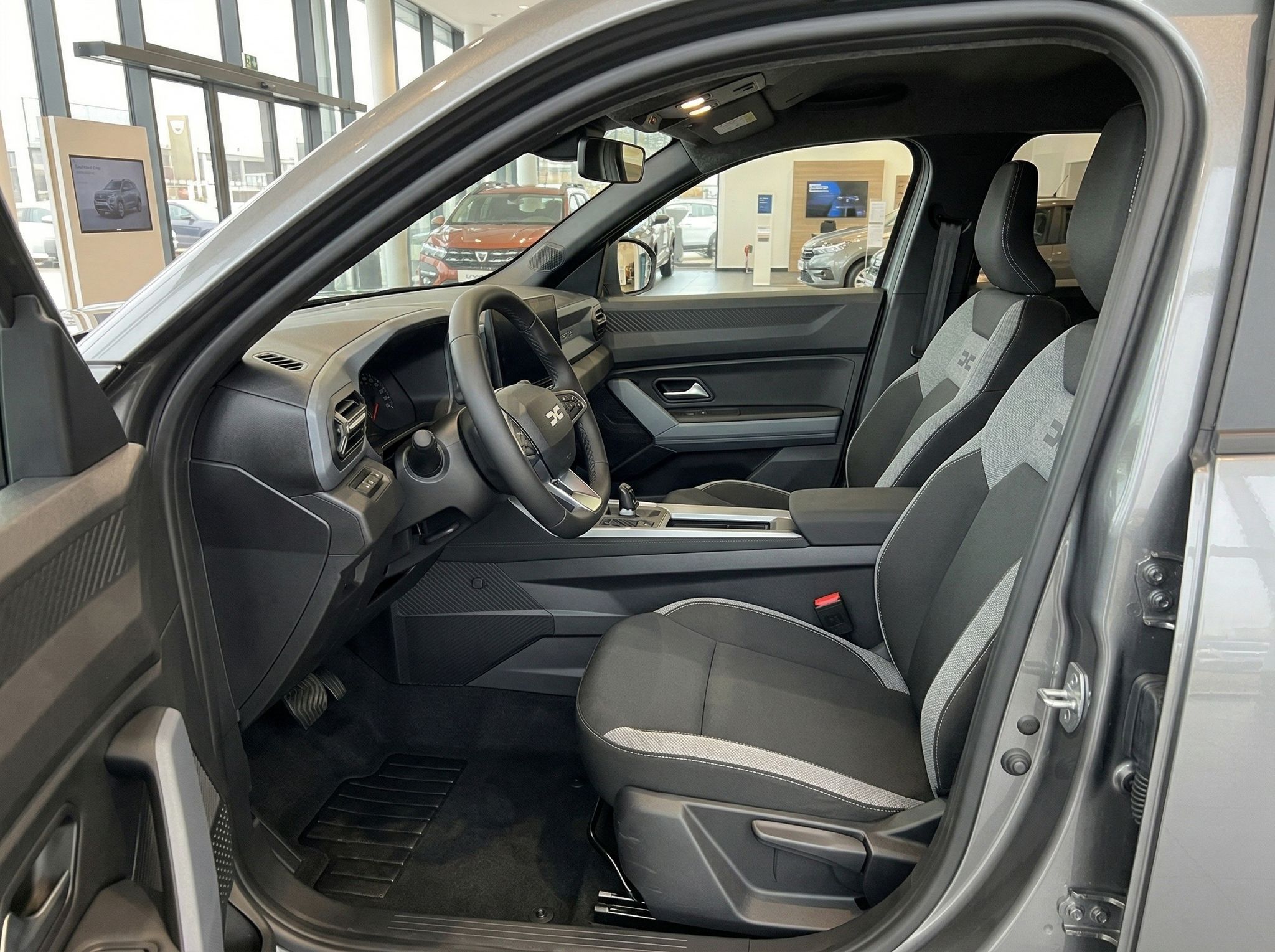 PKW Innenraum Fahrersitz mit grau-schwarzer Polsterung und Sicherheitsgurt im Autohaus