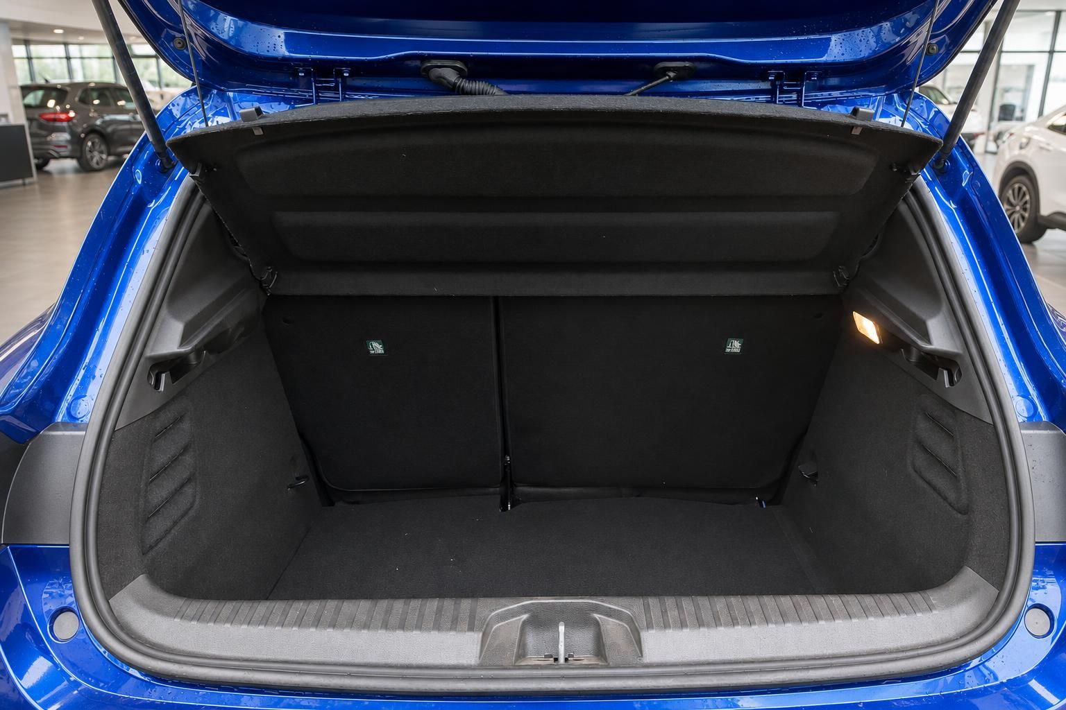 Geöffneter Kofferraum eines blauen Fahrzeugs mit schwarzer Innenausstattung und umgeklappten Rücksitzen