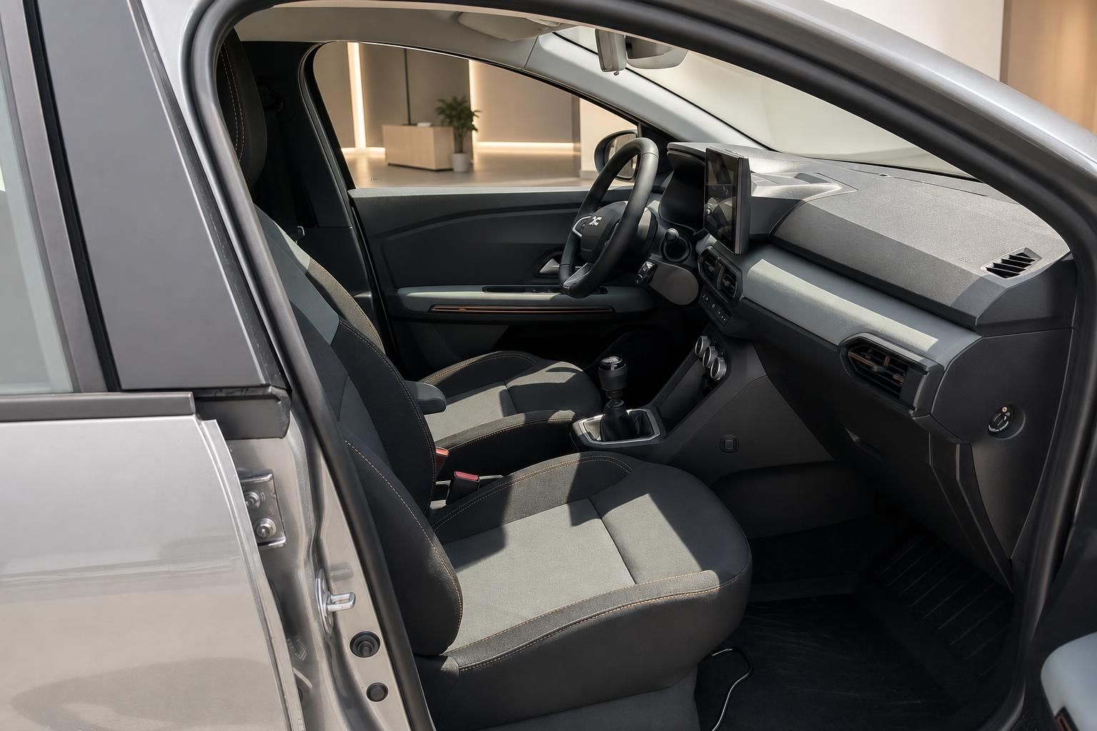 Dacia Innenraum Vordersitze mit schwarzem Stoff, Schaltgetriebe und Armaturenbrett