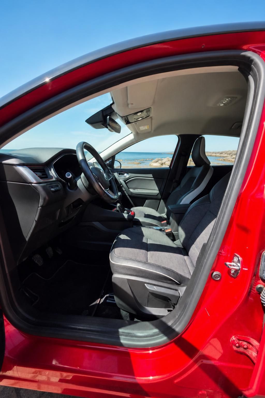 Innenraum eines roten Fahrzeugs mit Blick auf Meer und Kueste