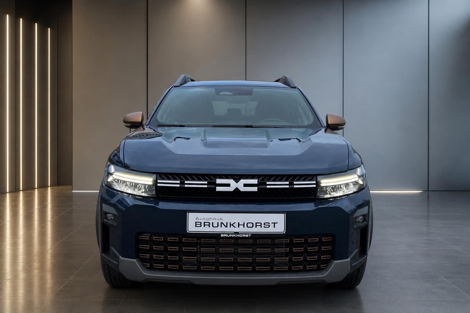 Dacia SUV Frontansicht blau mit LED-Tagfahrlicht und charakteristischem Kühlergrill im Autohaus