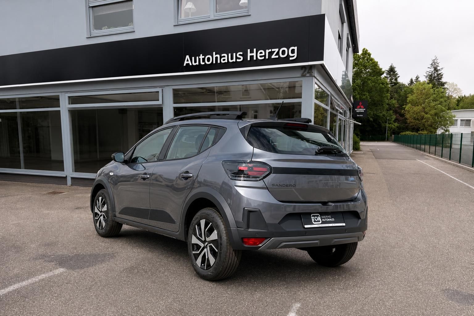 Dacia Sandero grau Heckansicht seitlich vor Autohaus Herzog