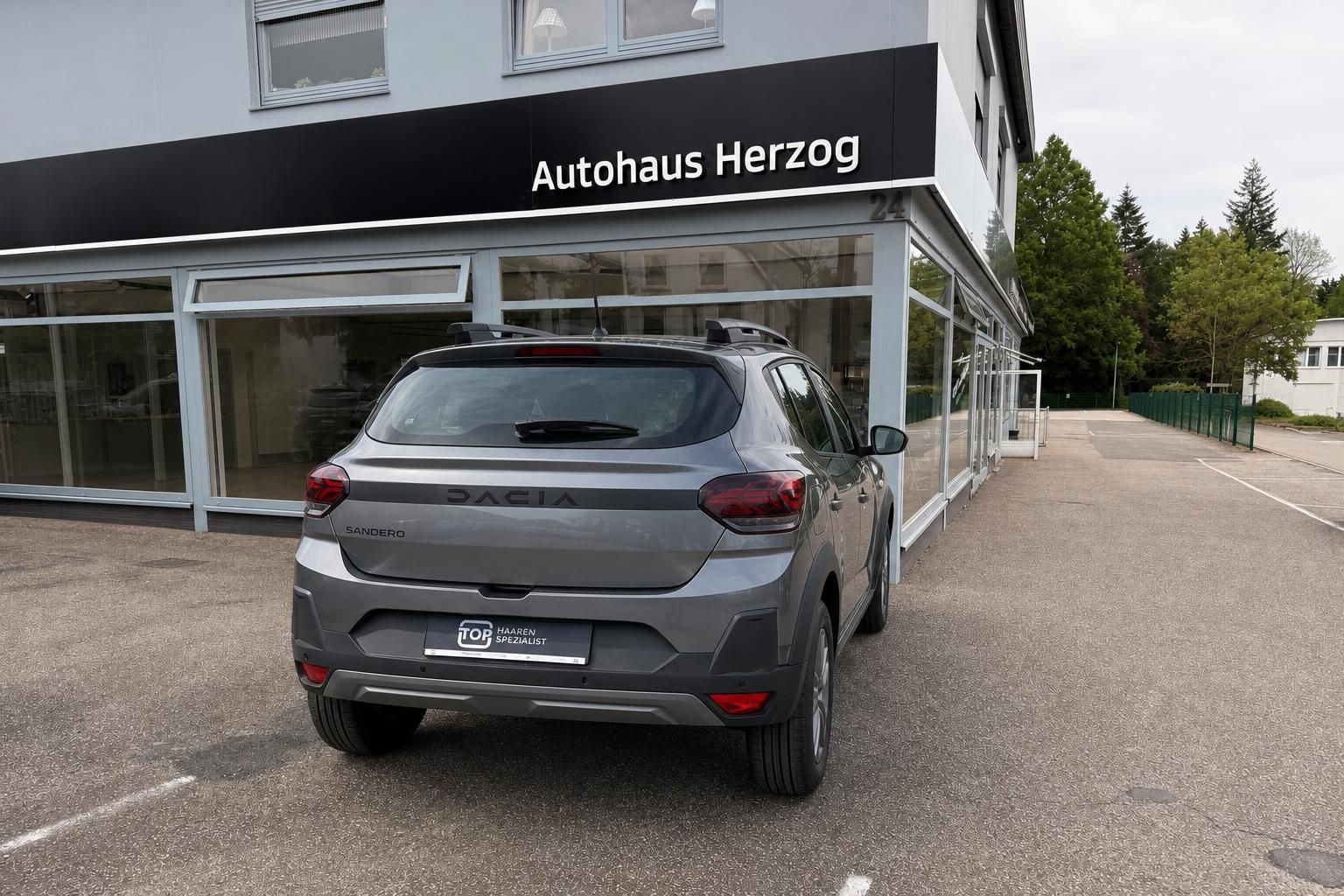 Dacia Sandero grau direkte Heckansicht vor Autohaus Herzog