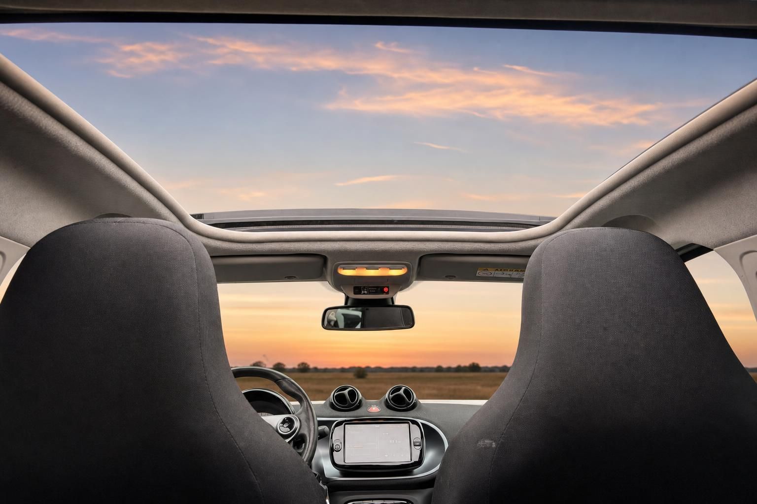 Smart Fortwo Innenraum mit Panoramadach und Blick durch Frontscheibe bei Sonnenuntergang