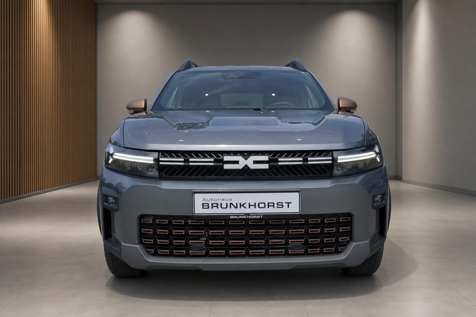 Grauer Dacia SUV Frontansicht mit LED-Scheinwerfern im Autohaus Showroom