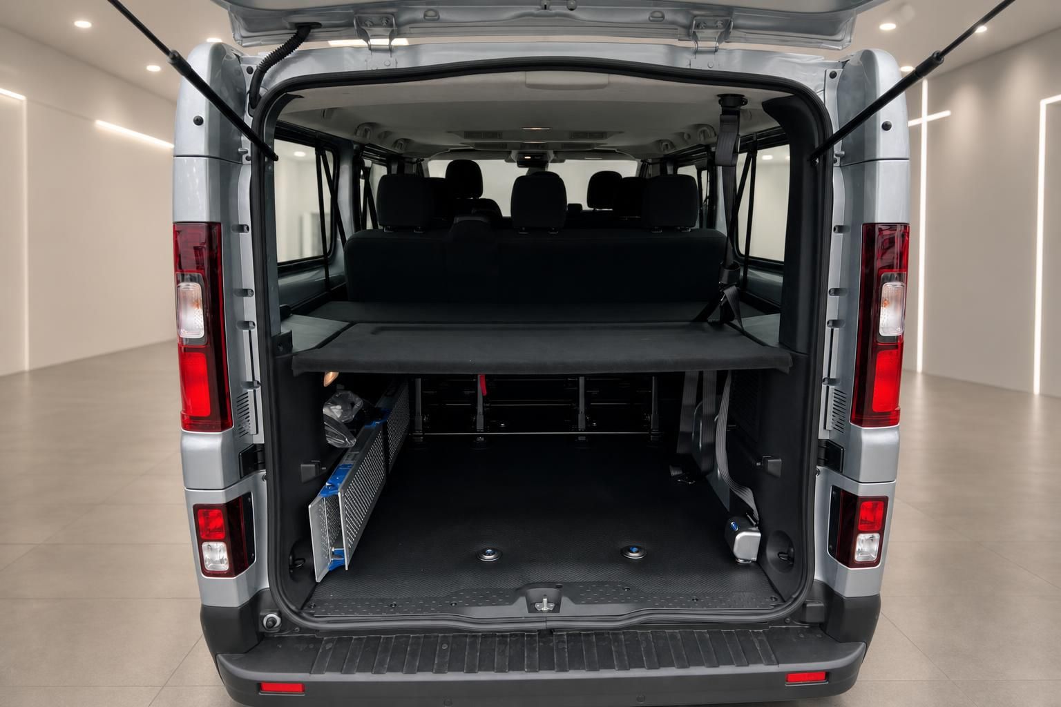 Kofferraum eines silbernen Transporters mit geöffneter Heckklappe und Ladeboden in Showroom