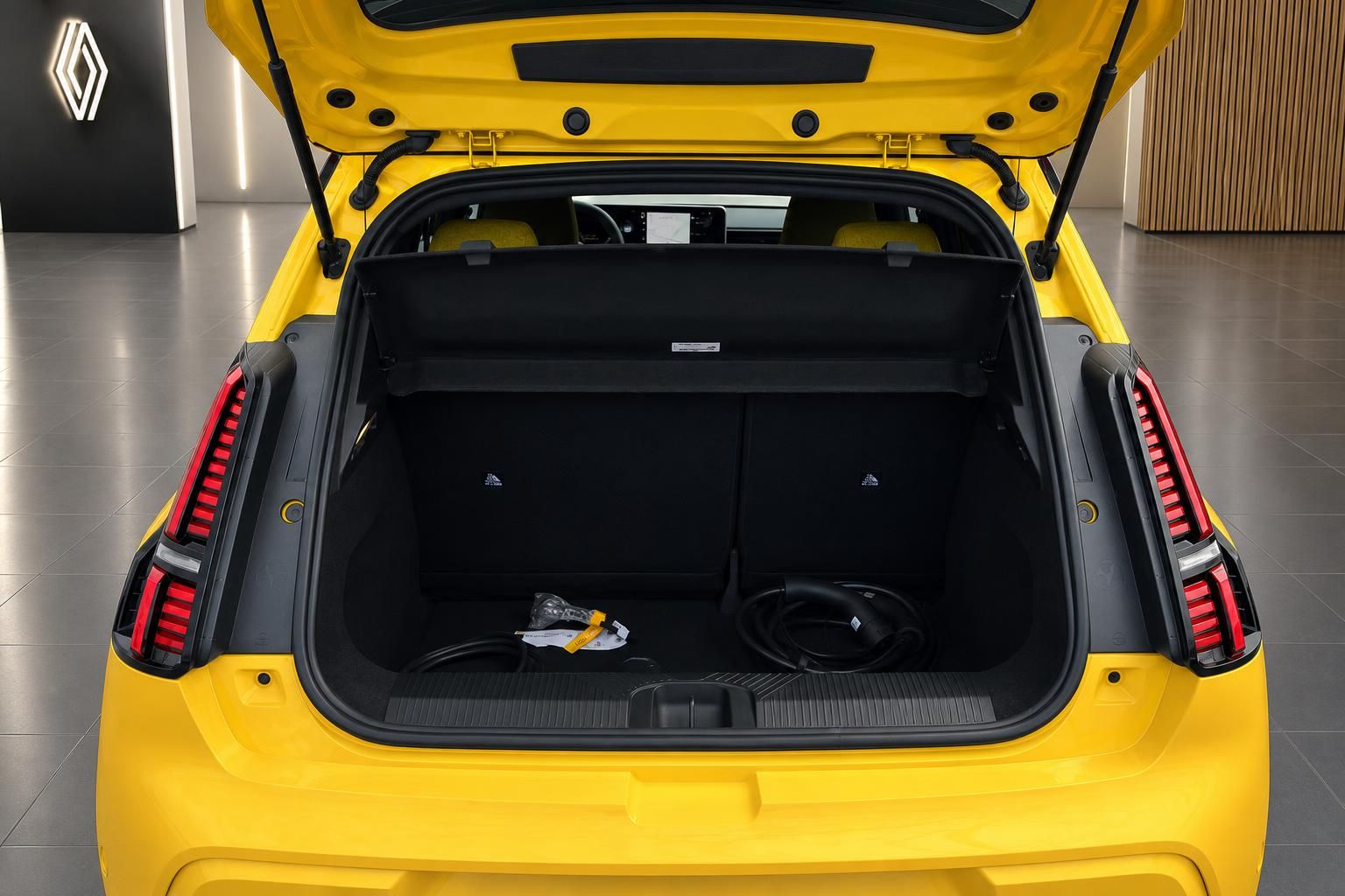 Renault 5 Elektro gelb geöffneter Kofferraum mit Ladekabel und LED-Rückleuchten im Autohaus
