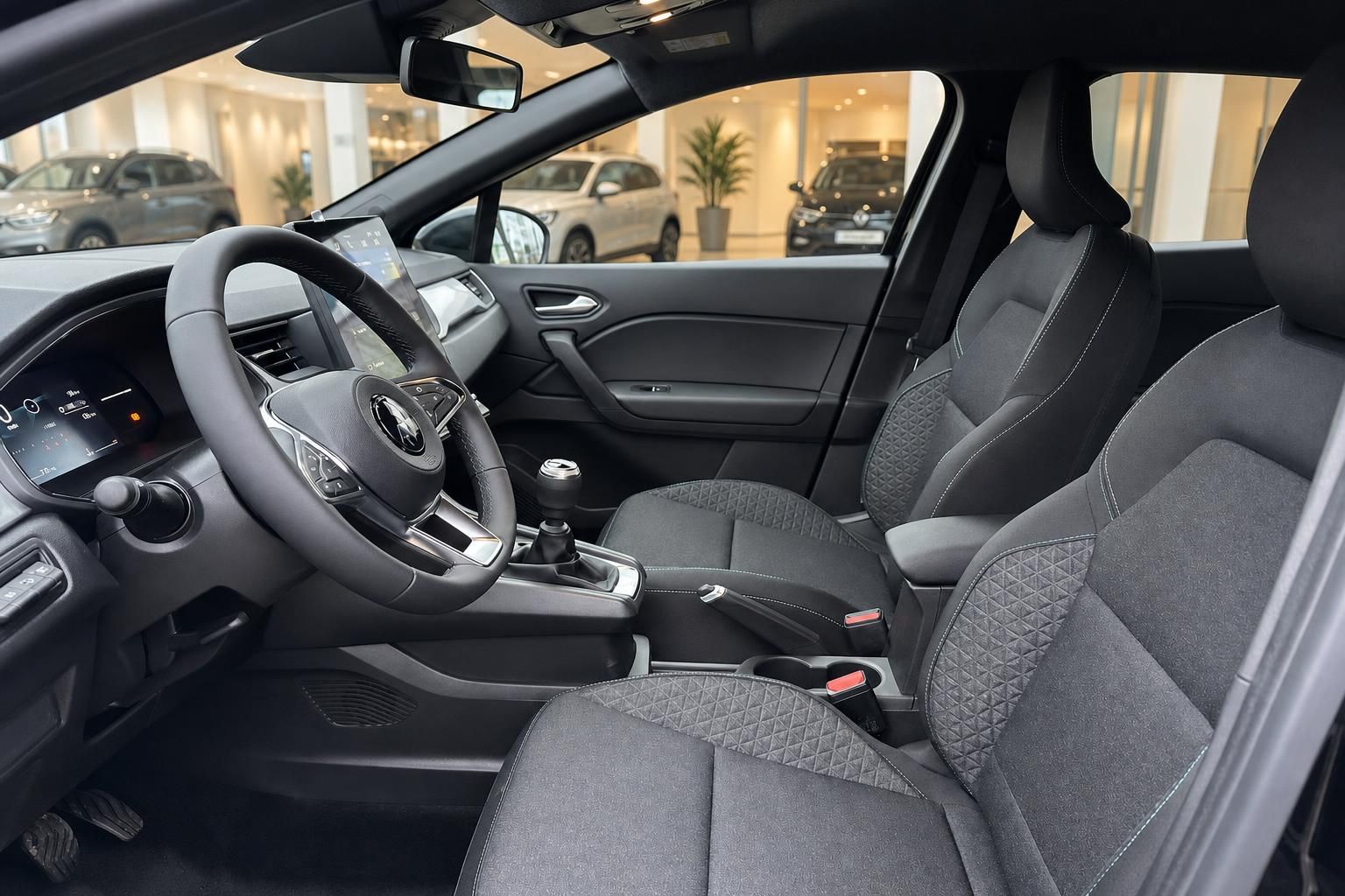 Renault Clio Innenraum mit Lenkrad, Schaltgetriebe und schwarzen Stoffsitzen im Autohaus