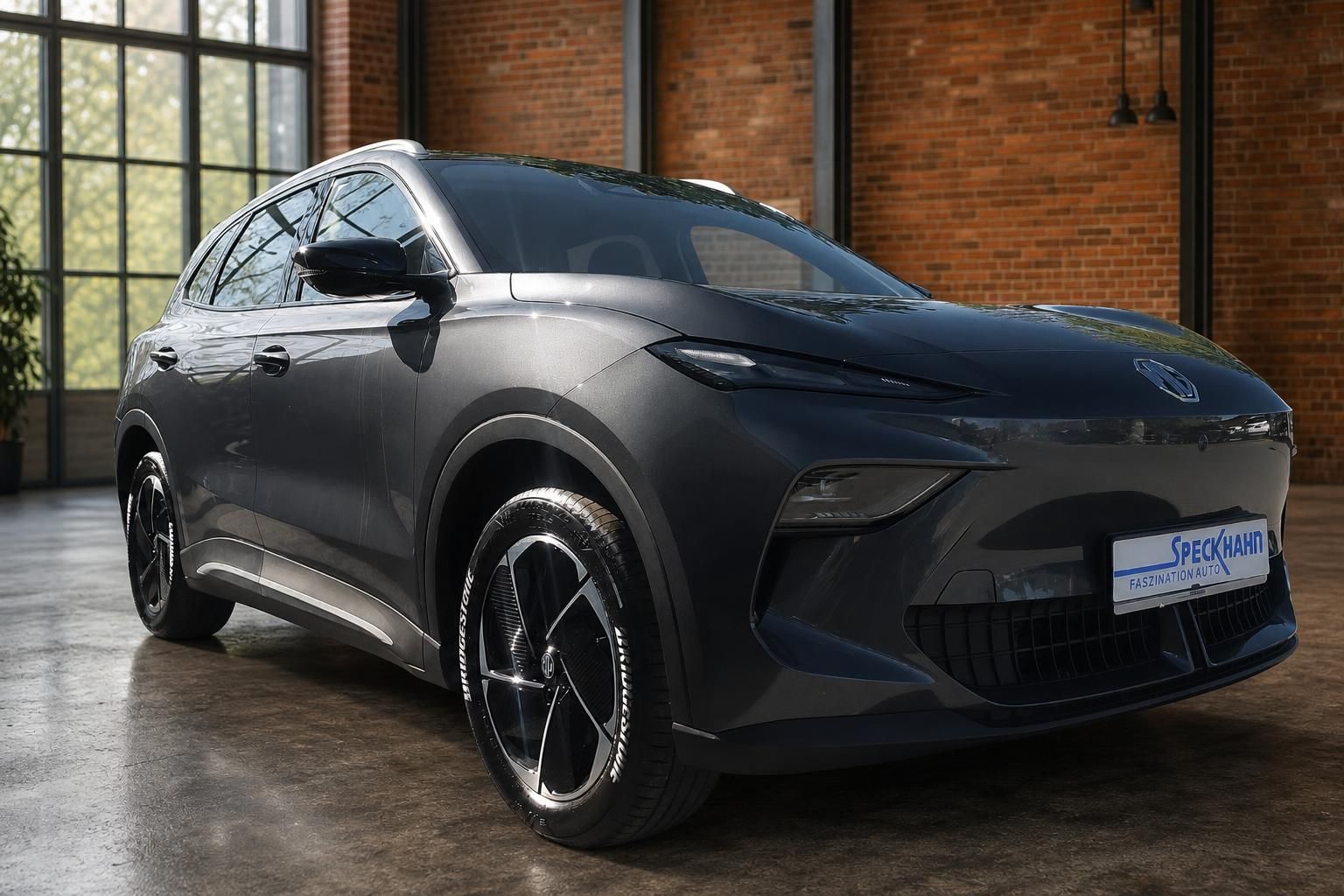 MG SUV in Grau-Metallic, Frontansicht schräg in Loft-Ambiente