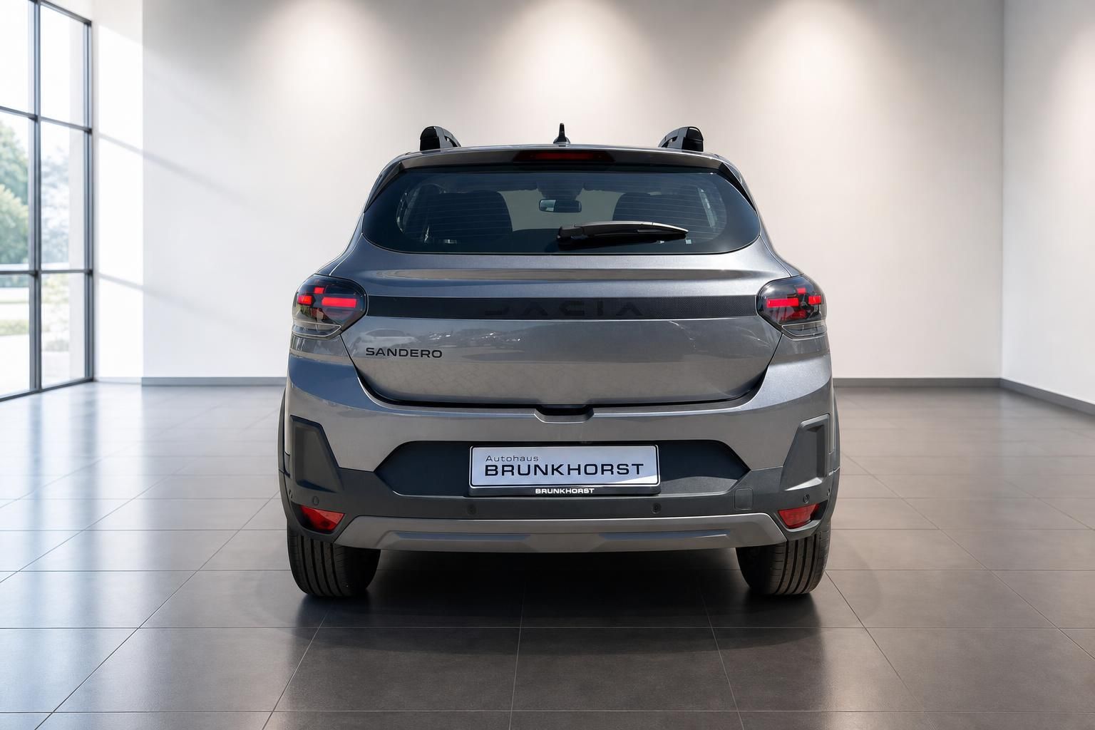Dacia Sandero Heckansicht in grau, Rückleuchten und Heckklappe im modernen Autohaus Showroom