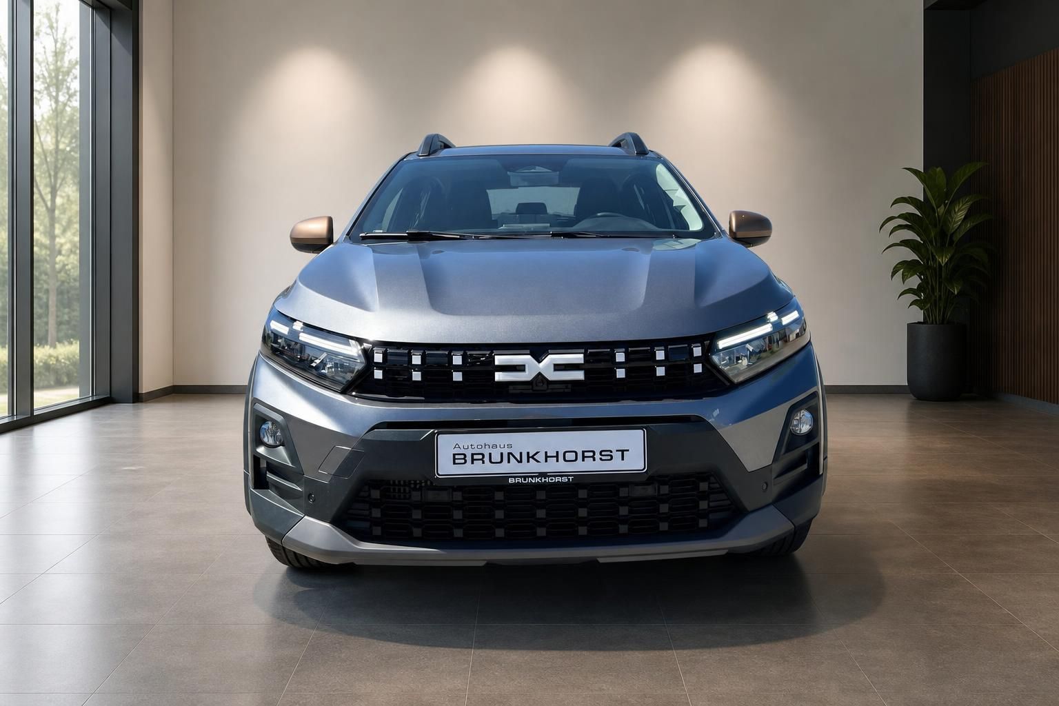 Dacia Sandero Frontansicht in blau-grau, LED-Scheinwerfer und markanter Kühlergrill im Autohaus