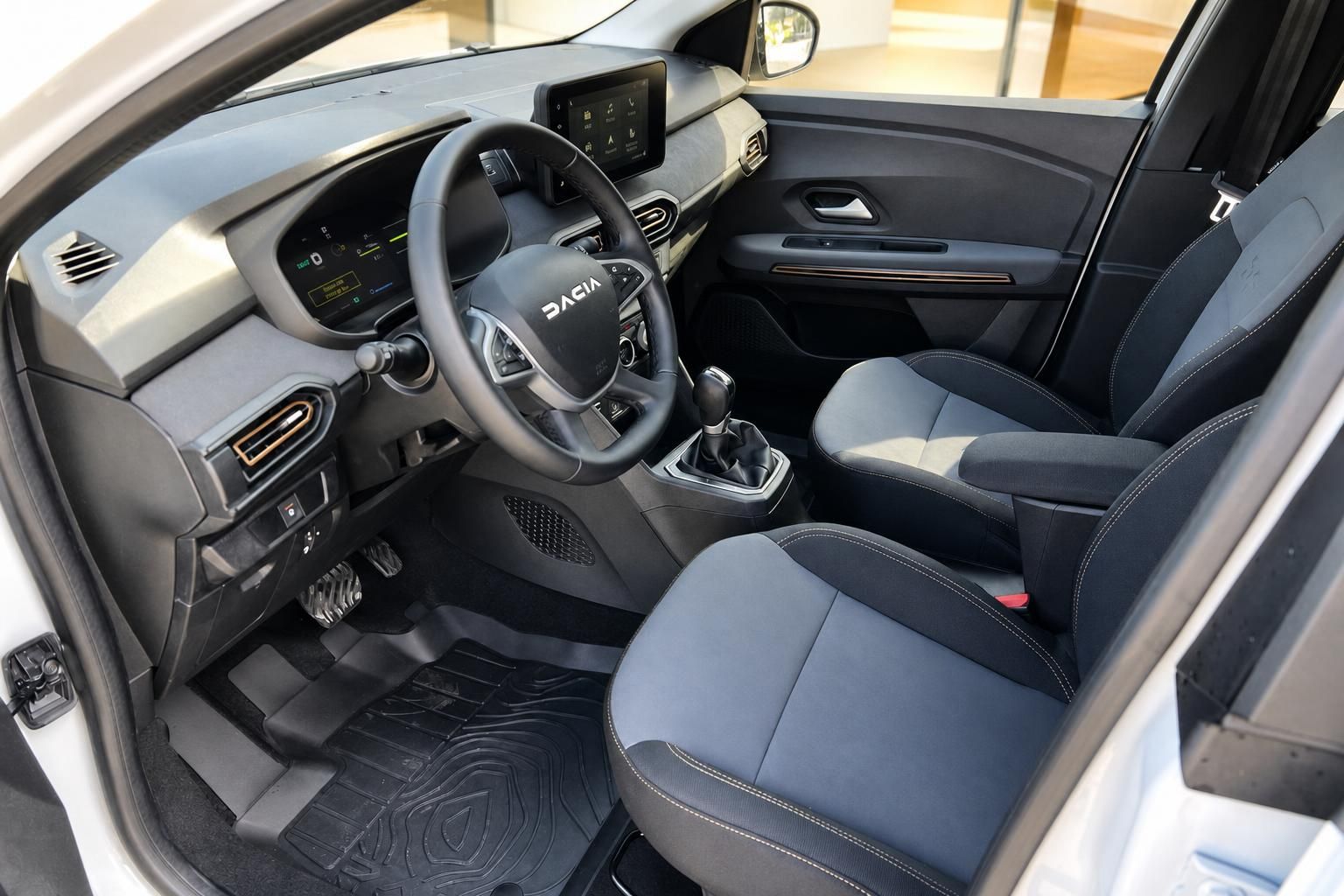 Dacia Fahrersitz und Cockpit-Bereich mit grau-schwarzer Innenausstattung und Schaltgetriebe