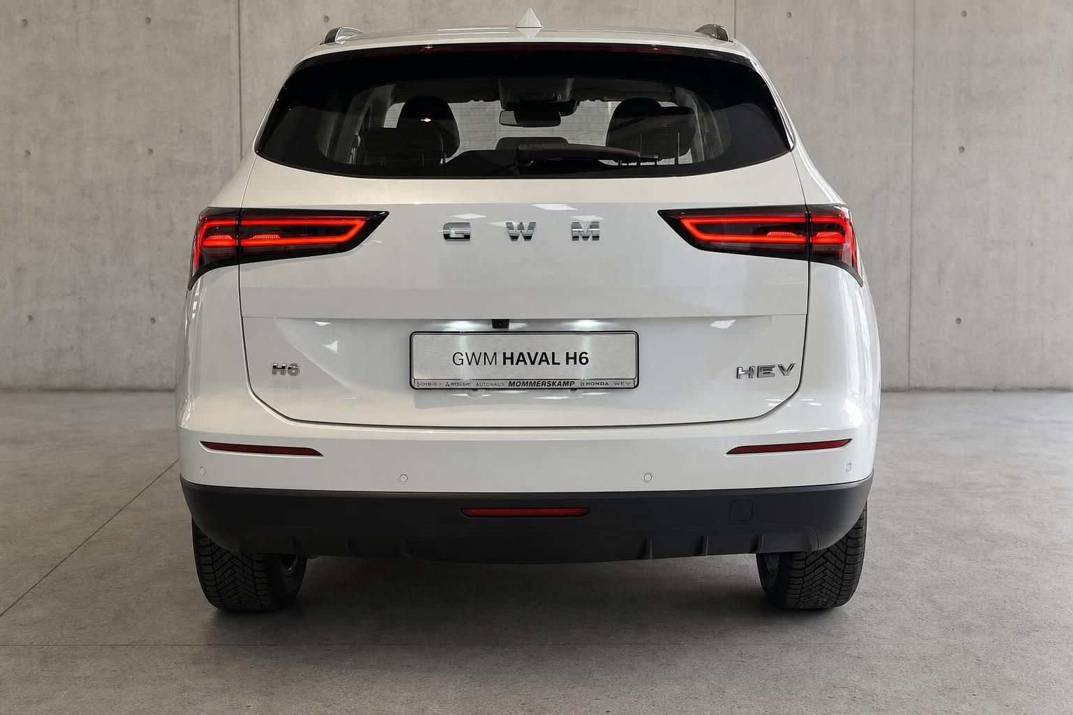 GWM Haval H6 HEV Heckansicht in Weiss vor Betonwand