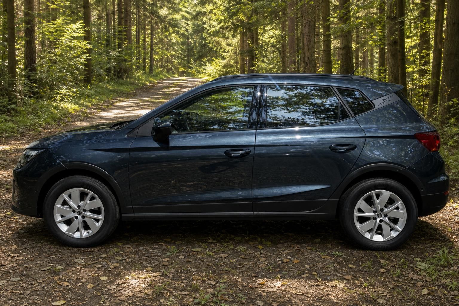 SEAT Arona SUV Seitenansicht links, dunkelgraue Lackierung mit Aluminiumfelgen im Waldweg