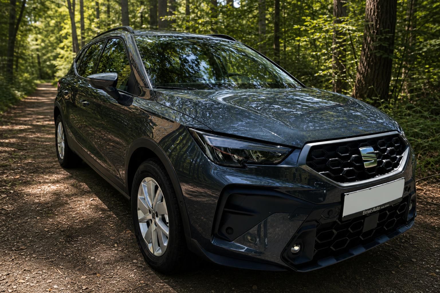 SEAT Arona SUV Schrägansicht vorne links, dunkelgrau mit Chromgrill in Waldumgebung