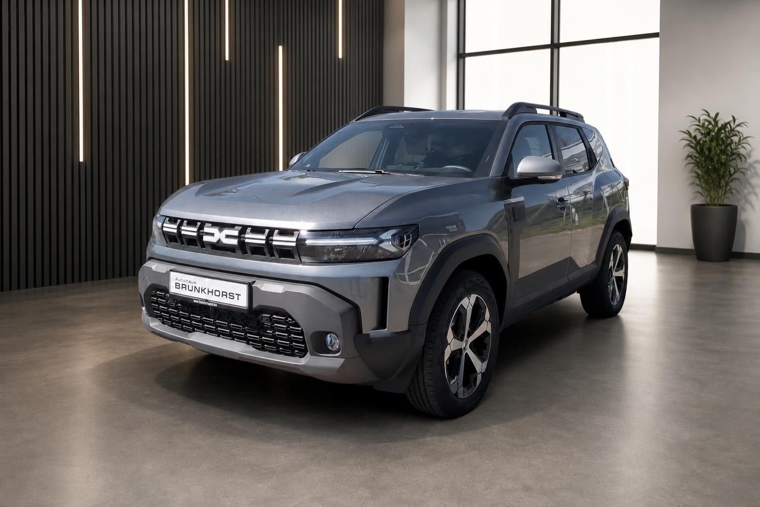 Dacia Duster SUV in grau, Seitenansicht im modernen Showroom bei Autohaus Brunkhorst