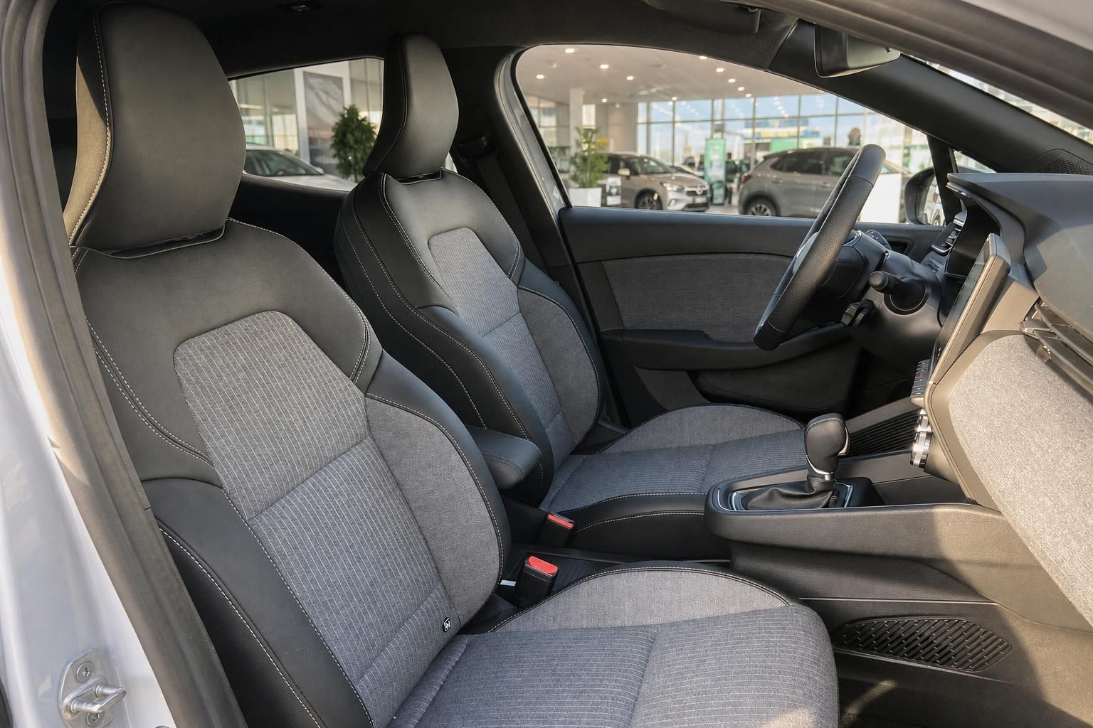 Fahrzeuginnenraum mit grauen Stoff-Sportsitzen, Mittelkonsole und Lenkrad im Autohaus