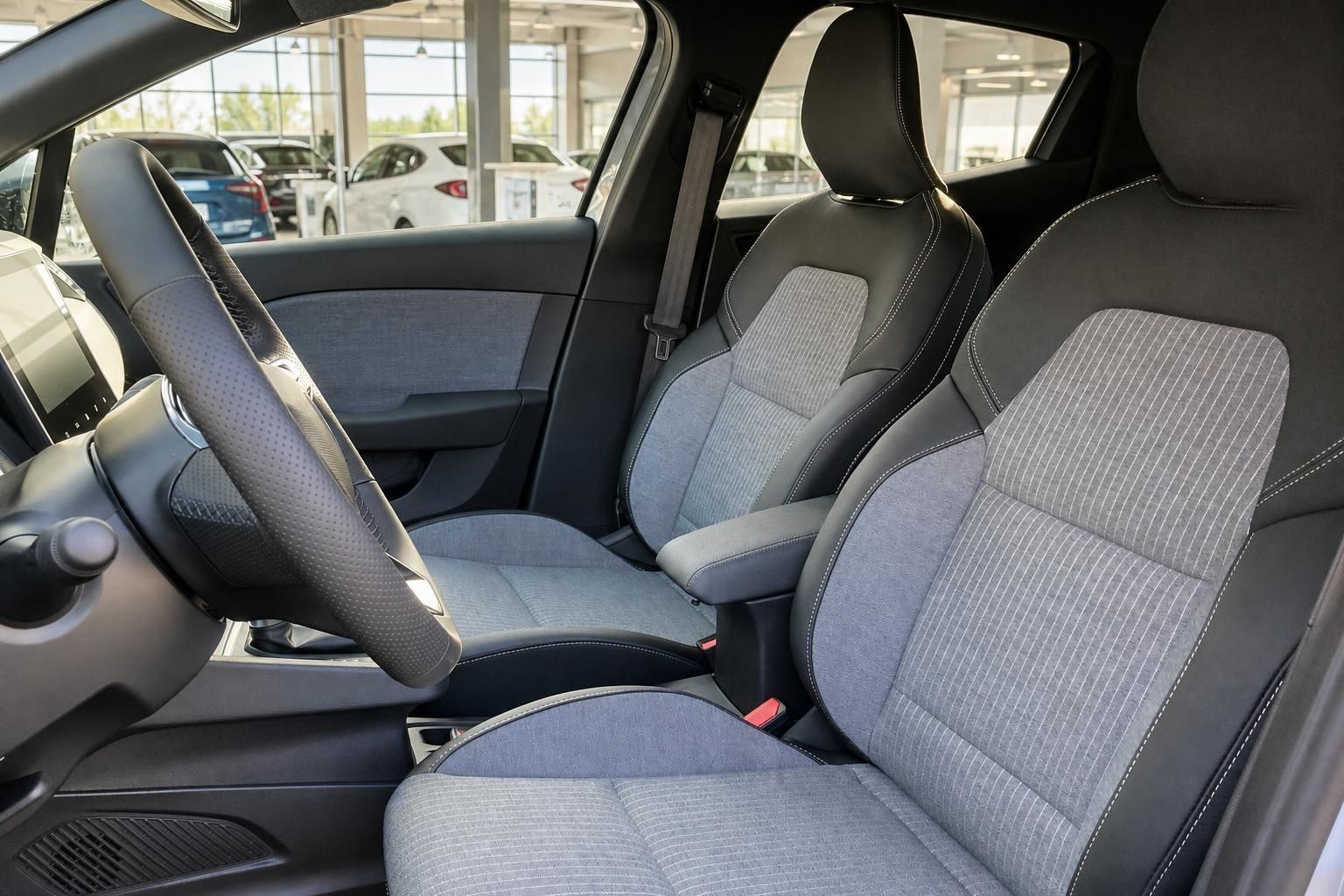 Vordersitze eines PKW mit grau-schwarzem Stoff-Leder-Bezug, Lenkrad und Mittelkonsole im Autohaus