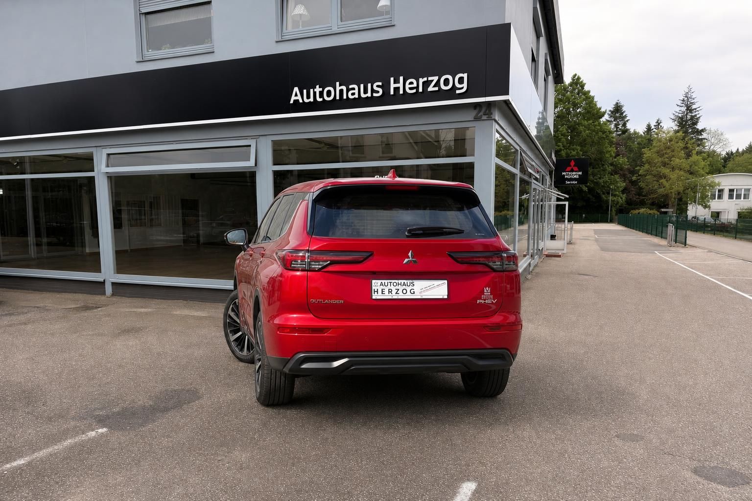 Roter Mitsubishi Outlander PHEV SUV Heckansicht vor Autohaus Herzog