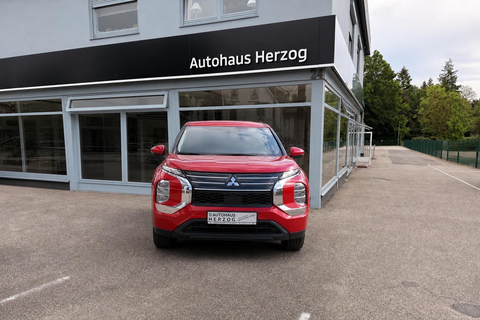 Roter Mitsubishi SUV Frontansicht vor Autohaus Herzog - elegantes Design mit charakteristischem Kühlergrill