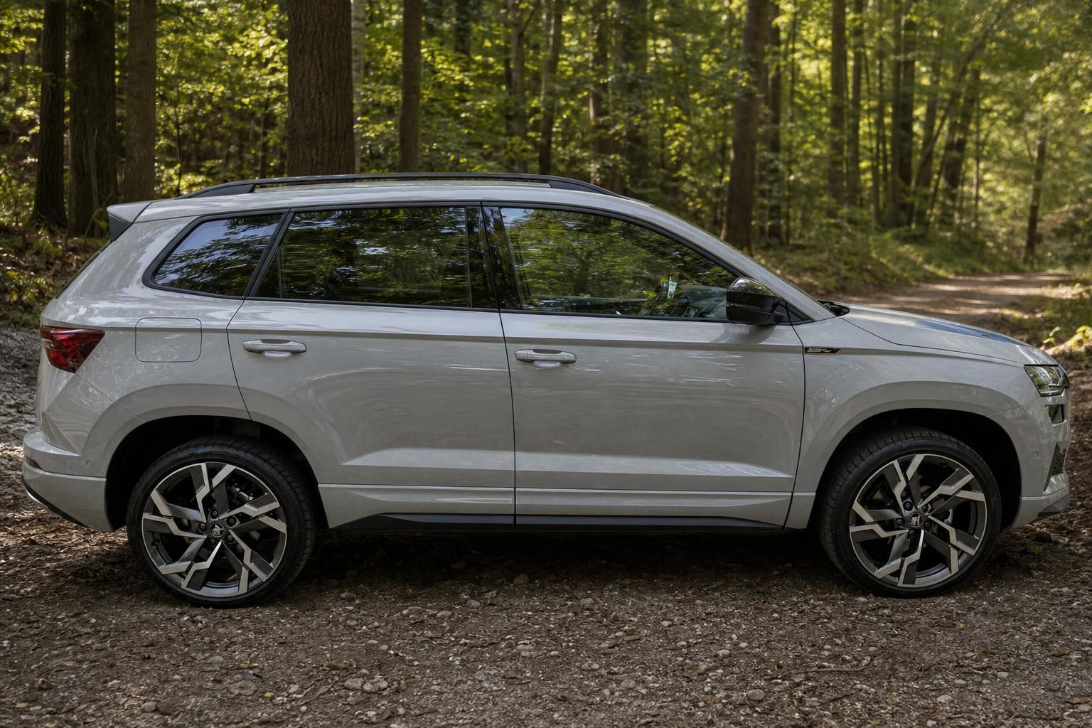 Grauer Skoda Karoq SUV seitlich geparkt im Wald mit Sportfelgen