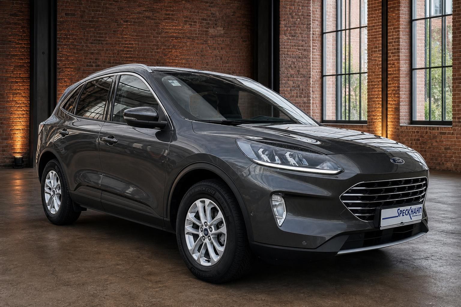 Ford Kuga in Grau, Frontansicht schräg vor Backsteinwand