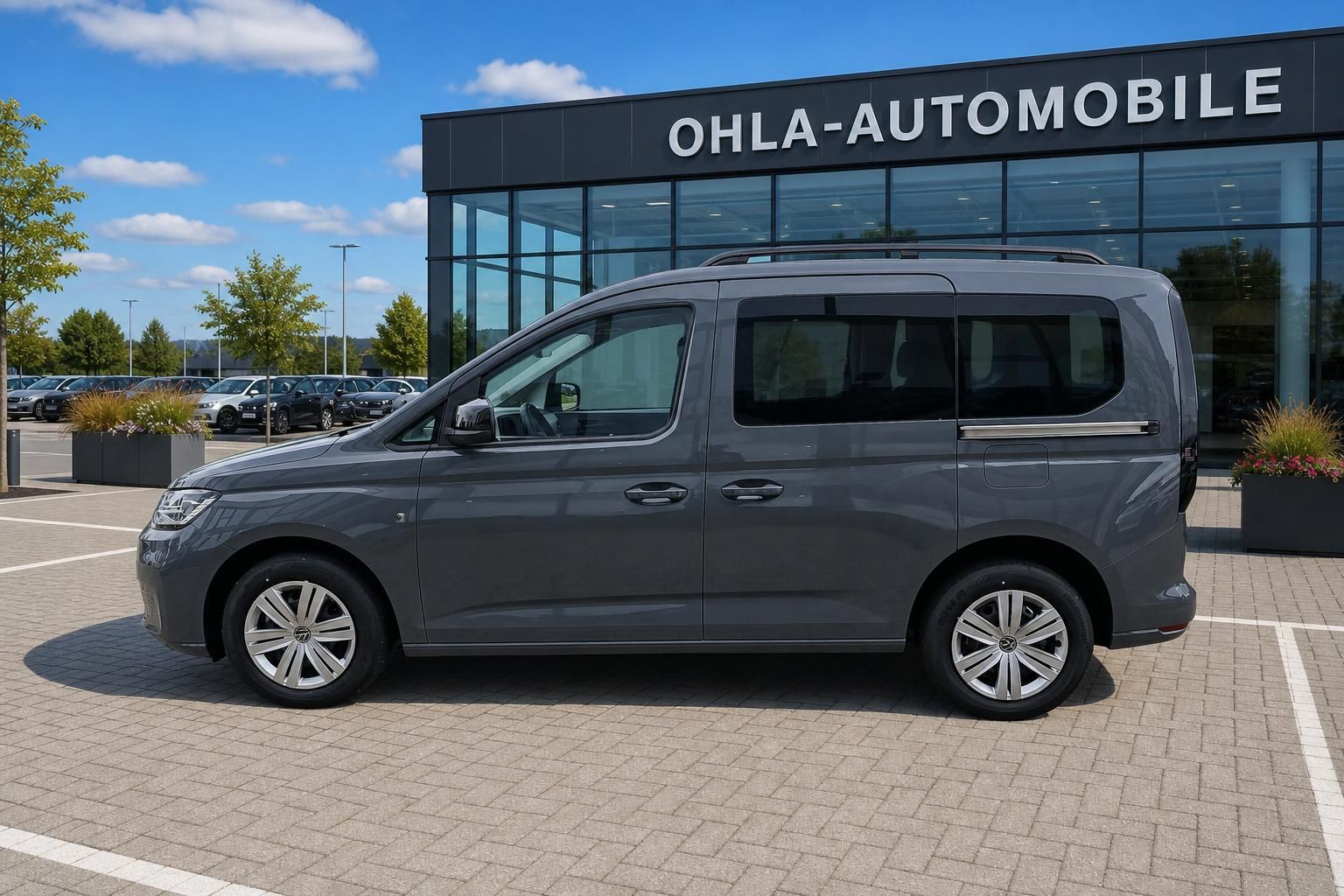VW Caddy grau Seitenansicht vor Autohaus Ohla-Automobile