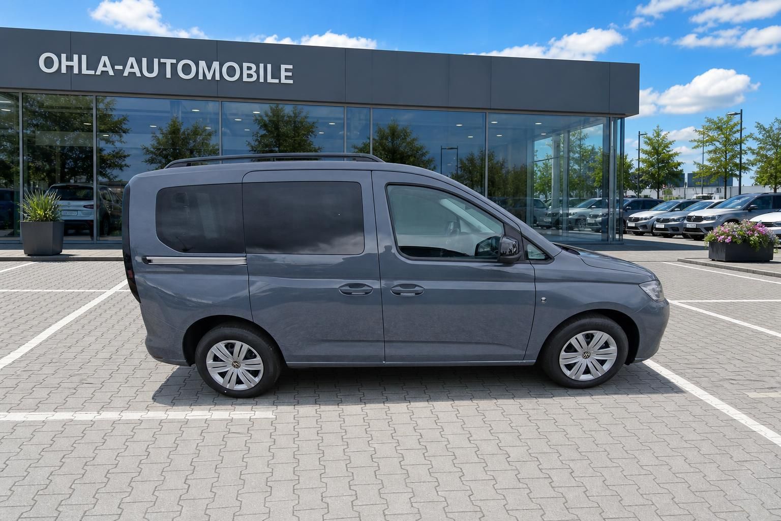 VW Caddy Neuwagen grau Seitenansicht komplett vor Autohaus