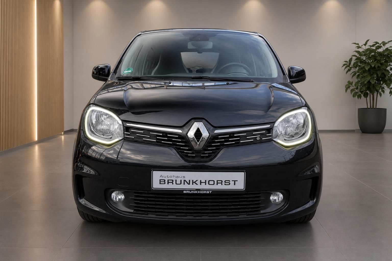 Renault Twingo schwarz, Frontansicht mit Scheinwerfern und Kühlergrill im modernen Showroom