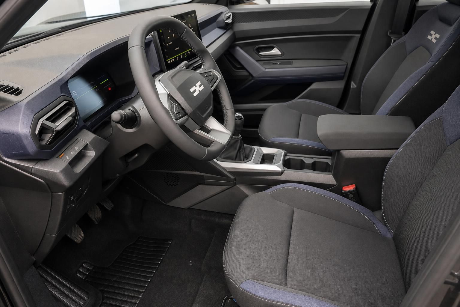 Dacia Fahrersitz Innenraum mit Lenkrad, Instrumententafel und blau-schwarzen Stoffsitzen