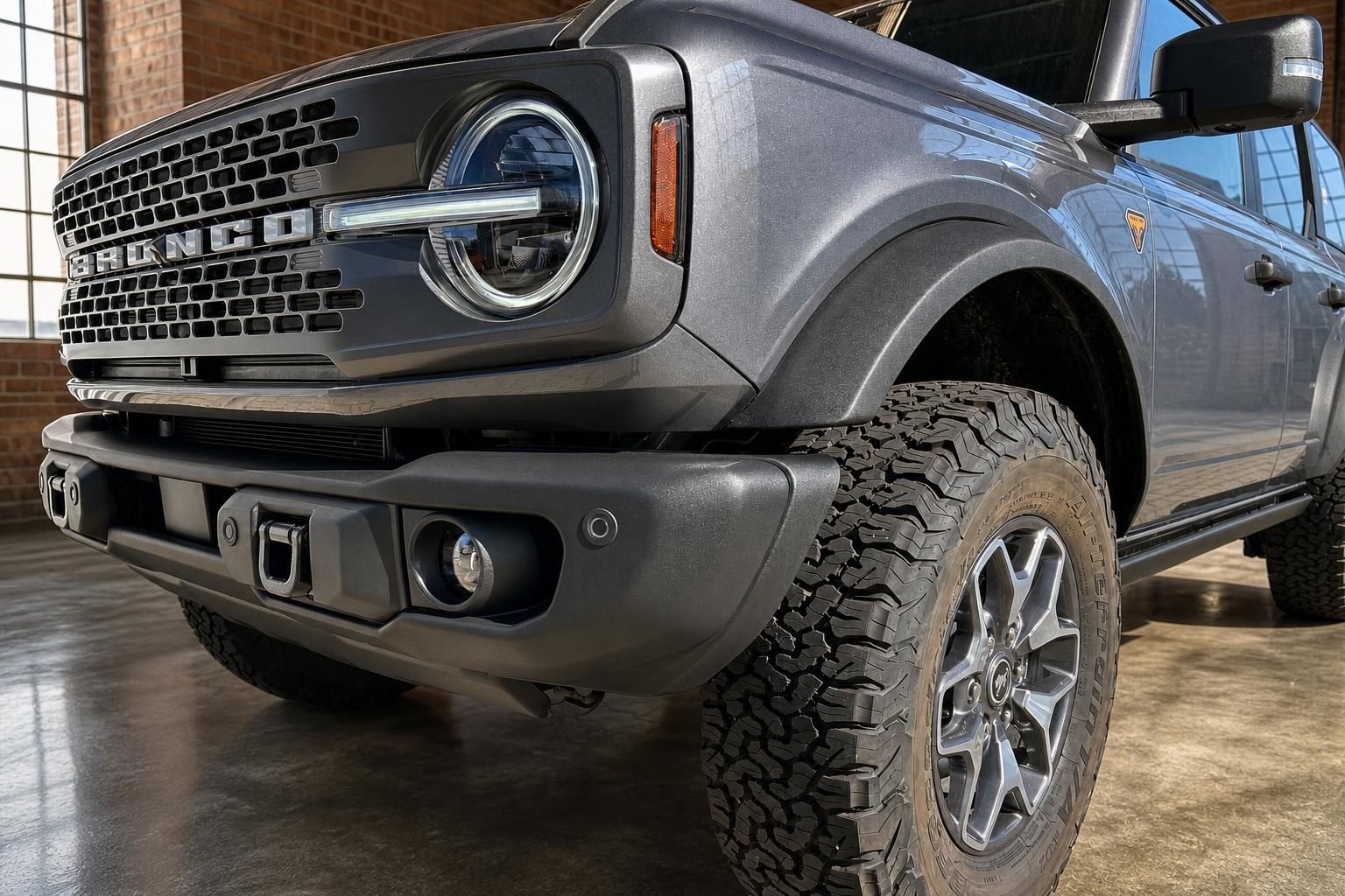 Ford Bronco grau Detailansicht Frontstoßstange Scheinwerfer und Geländereifen schräg