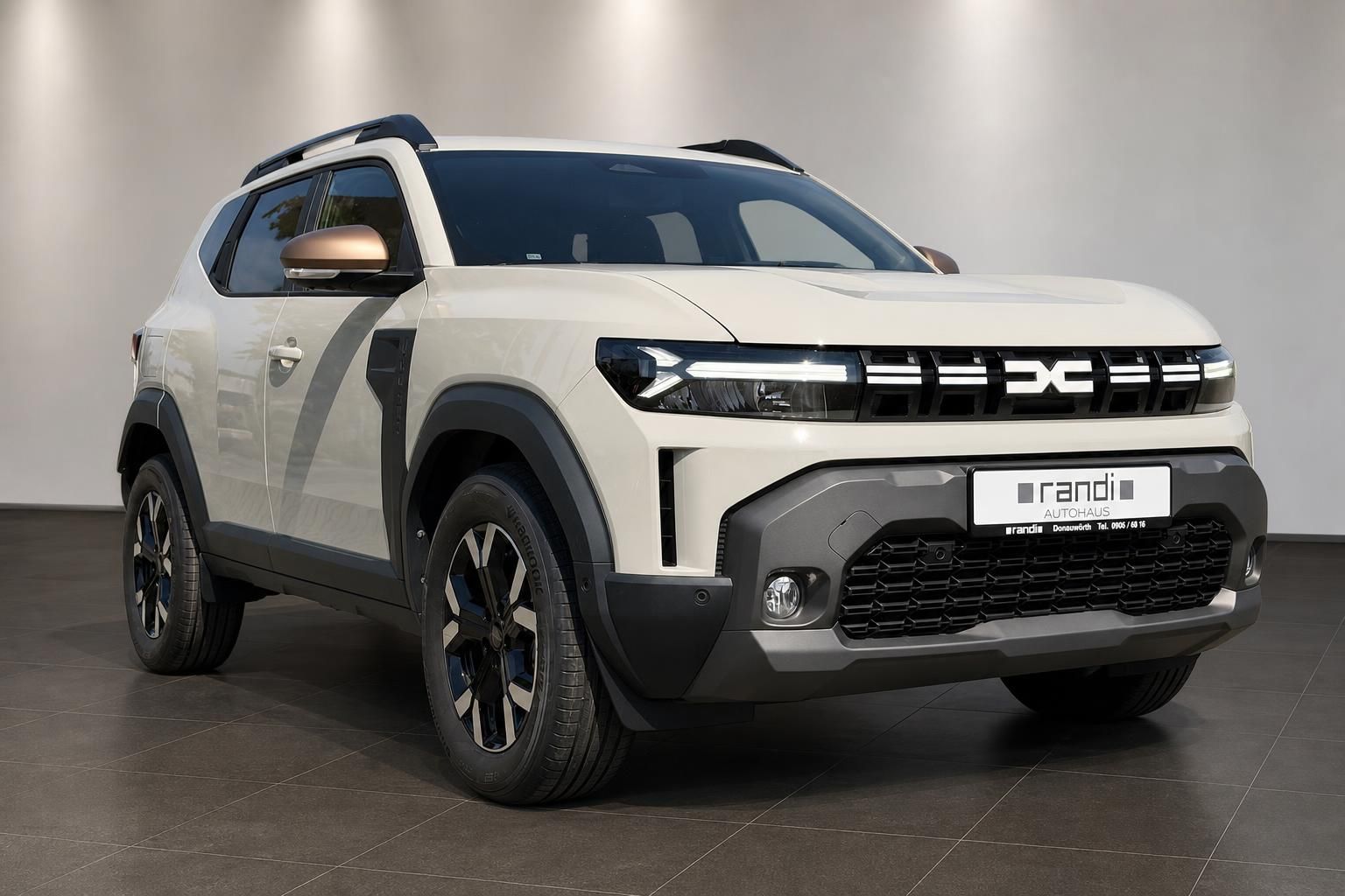Dacia Duster SUV in Beige Schrägansicht vorne rechts im Showroom Autohaus Randi
