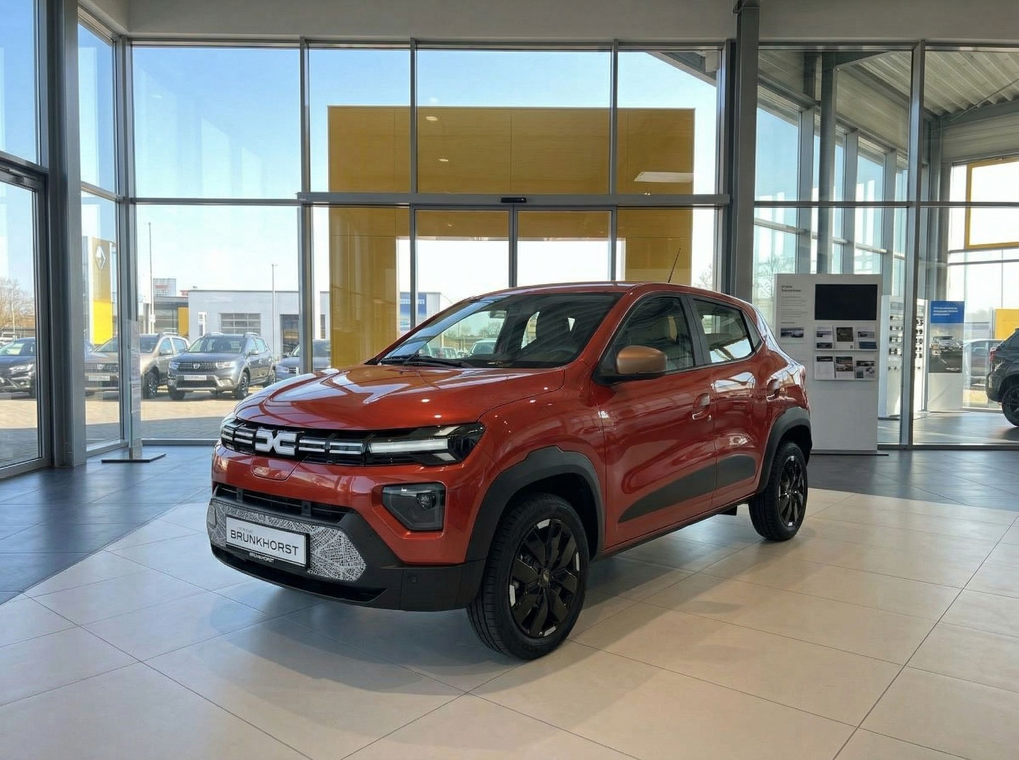 Orangenes Dacia SUV Fahrzeug im Autohaus Showroom - Seitenansicht mit schwarzen Felgen
