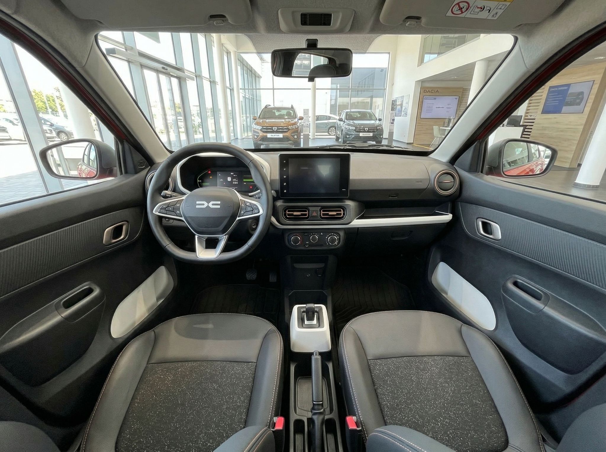 Dacia Fahrzeug Innenraum mit Lenkrad, Display und grau-weißer Sitzausstattung