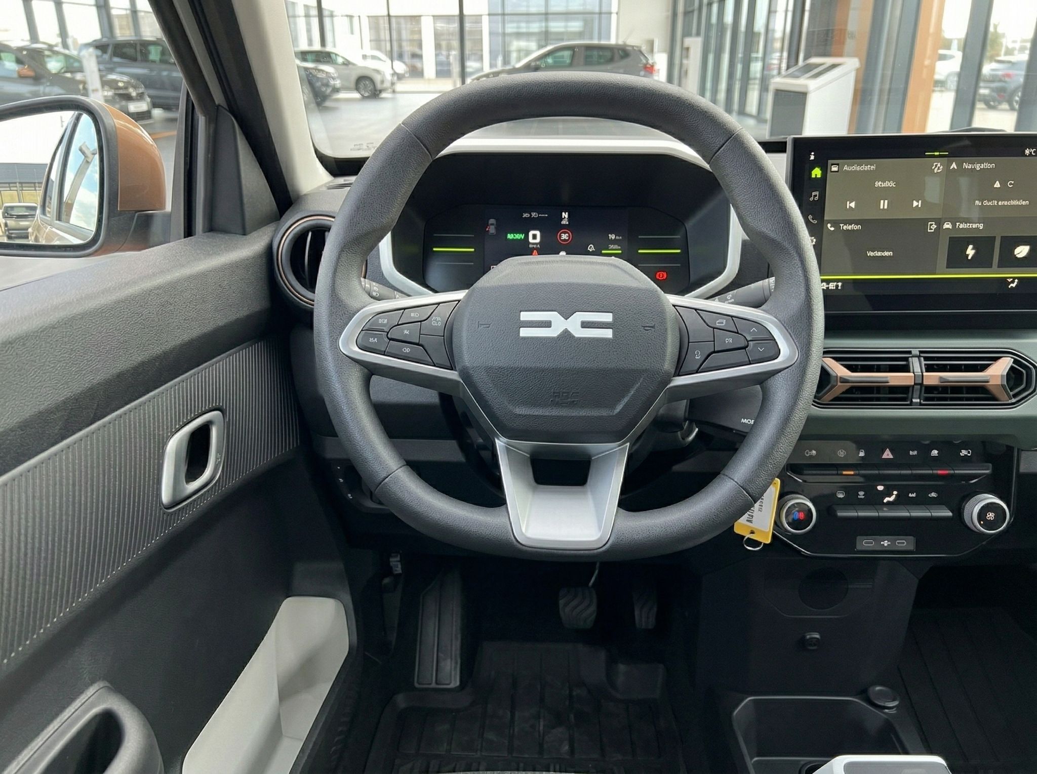 Detailansicht des Fahrzeug-Lenkrads mit Multifunktionstasten und digitalem Kombiinstrument im Hintergrund