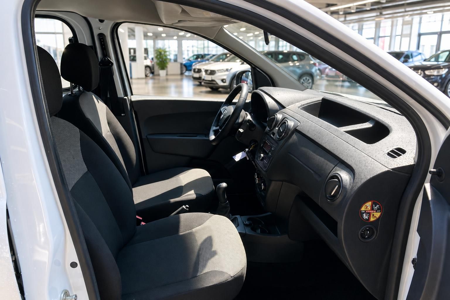 Dacia Fahrerseite Innenraum mit Vordersitzen, Lenkrad und geöffneter Tür im Autohaus
