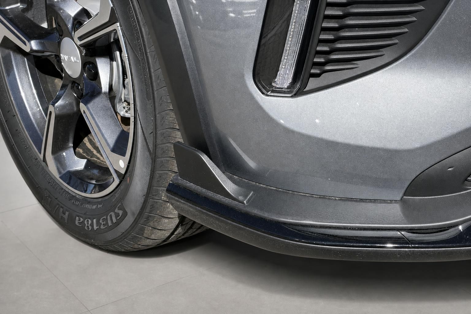 Detailaufnahme Rad und Frontstoßstange eines grauen SUV mit Leichtmetallfelge
