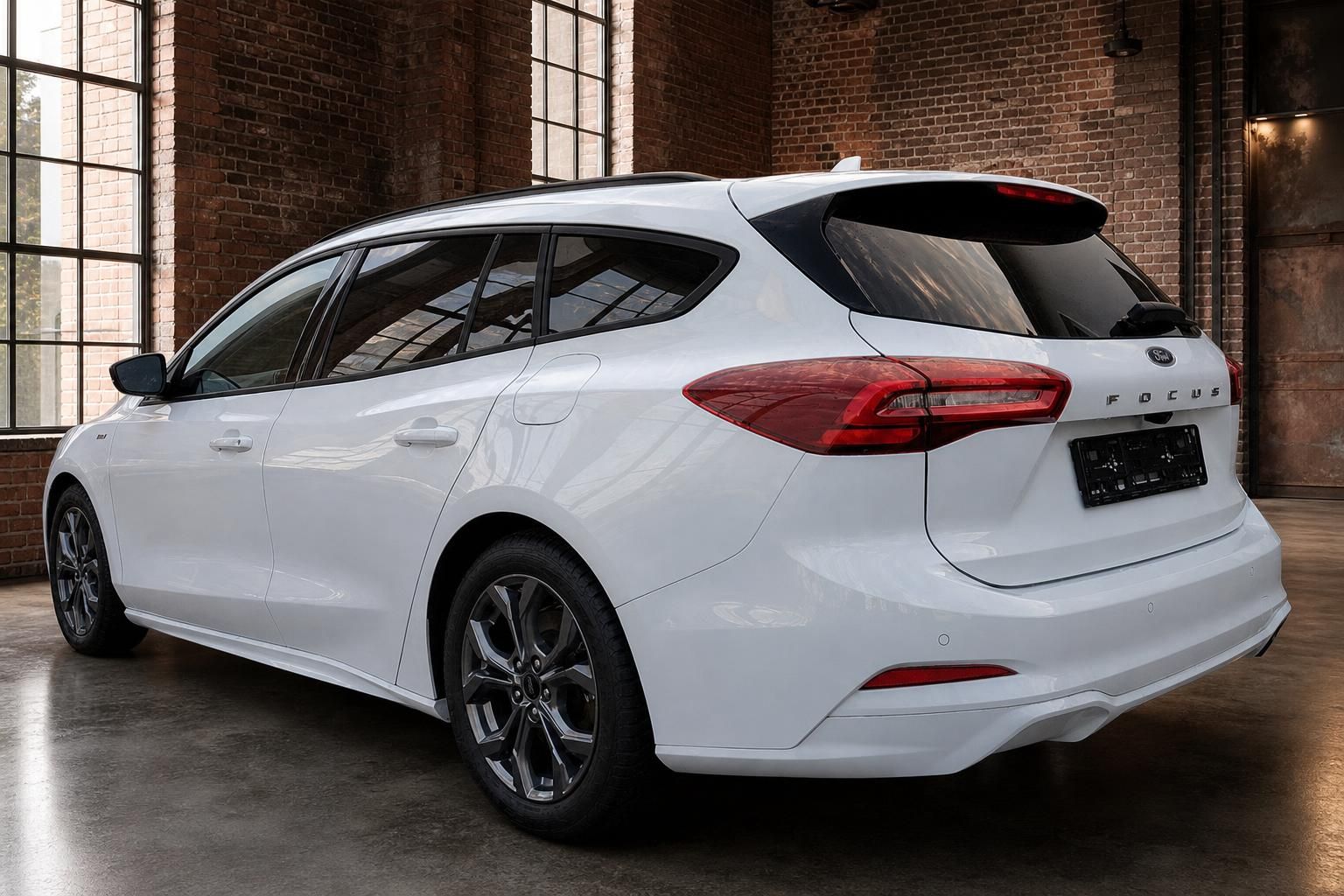 Ford Focus Turnier weiss Heckansicht schraeg links mit Alufelgen im Industrieloft