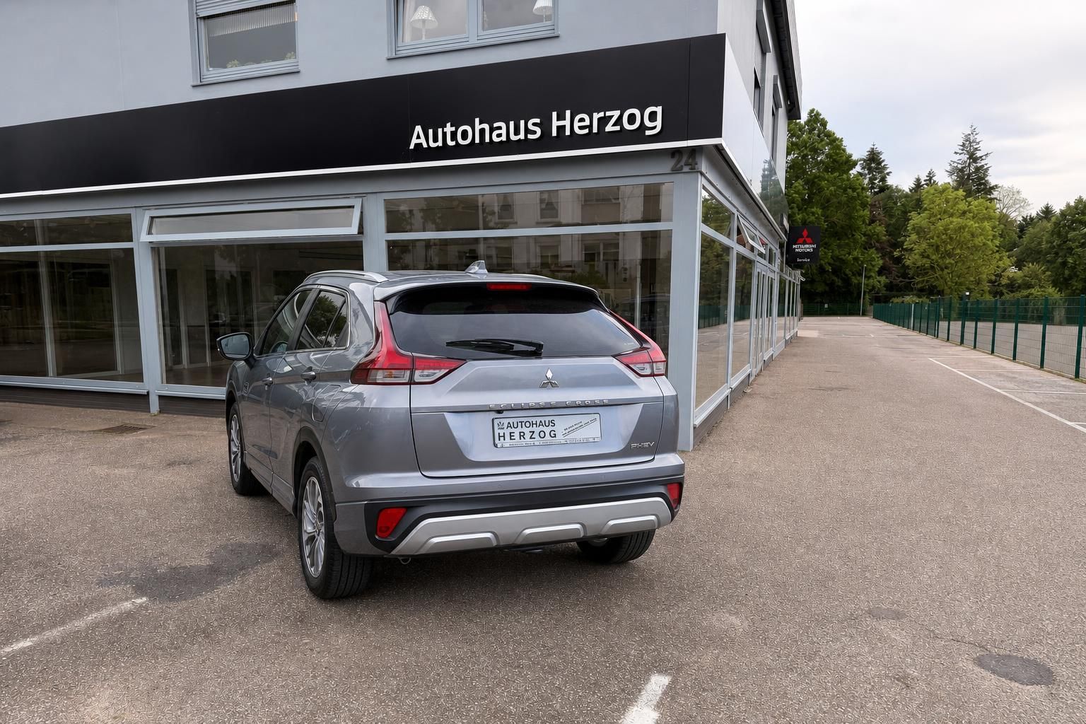 Mitsubishi Eclipse Cross PHEV Heckansicht in grau mit roter Akzentlinie und Autohaus Herzog Kennzeichen