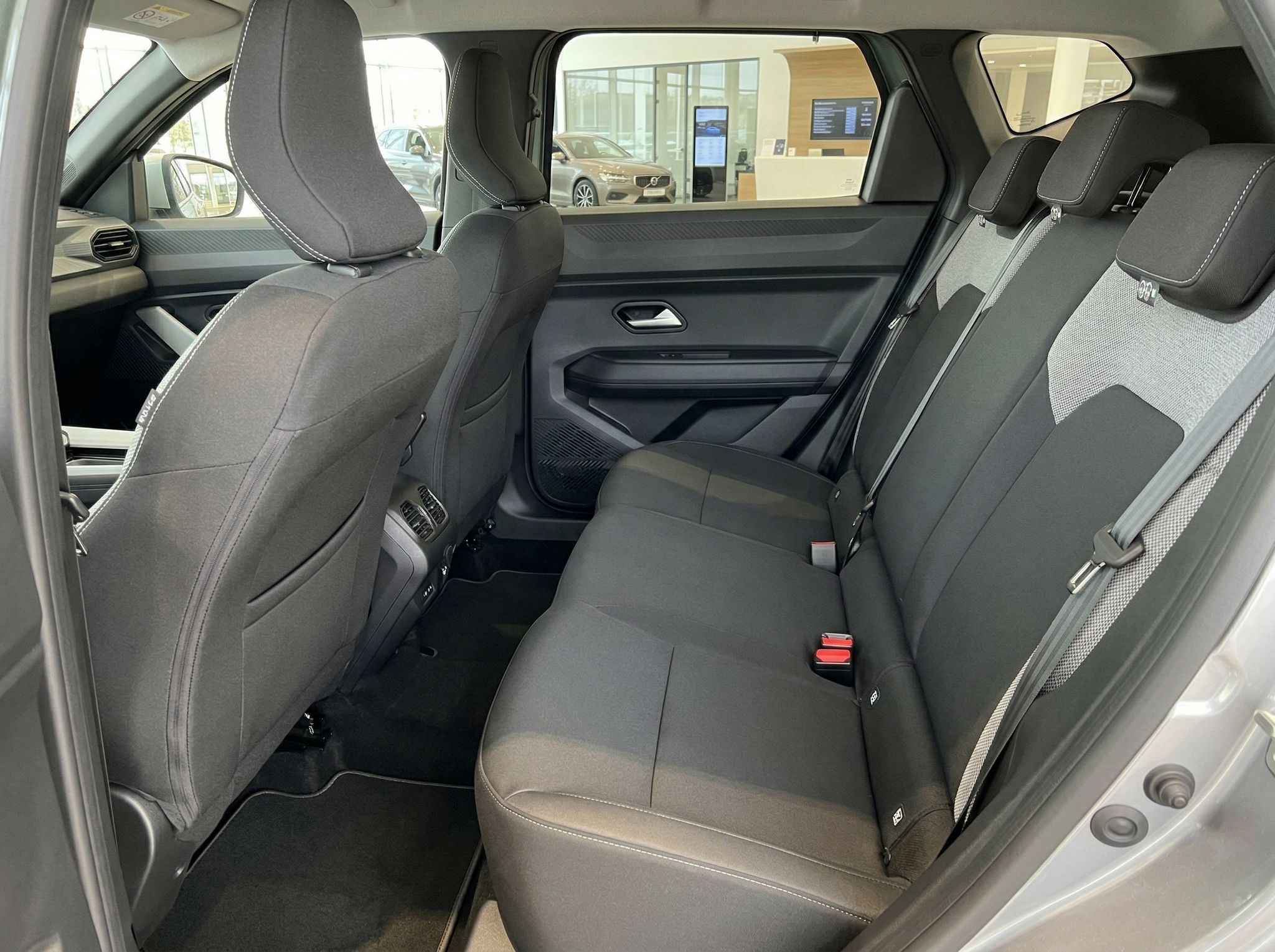 Rücksitzbank mit grauen Polstern und Sicherheitsgurten im Fahrzeuginnenraum