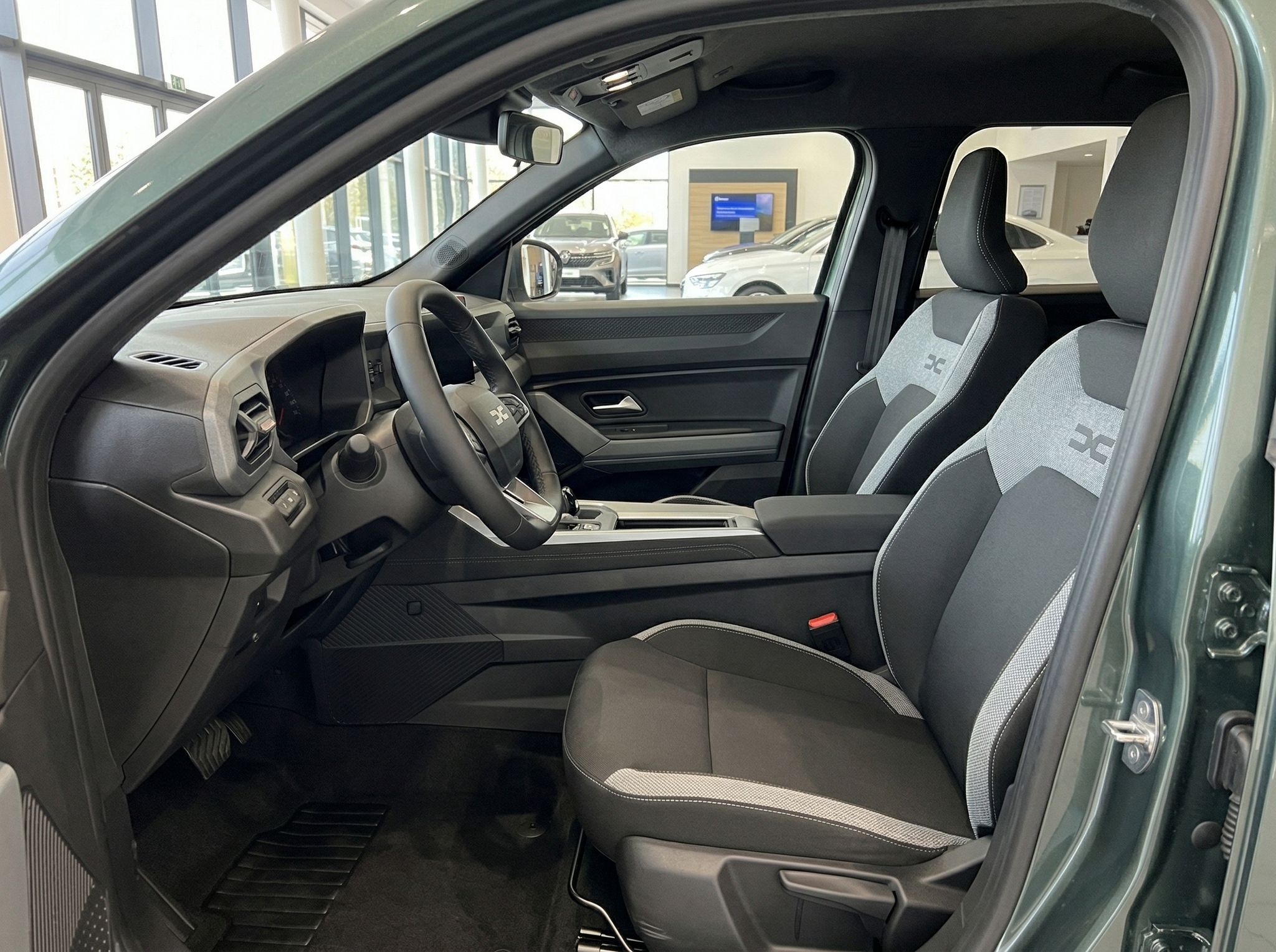 Fahrersitz und Innenraum eines Fahrzeugs mit grau-weißer Polsterung im Autohaus