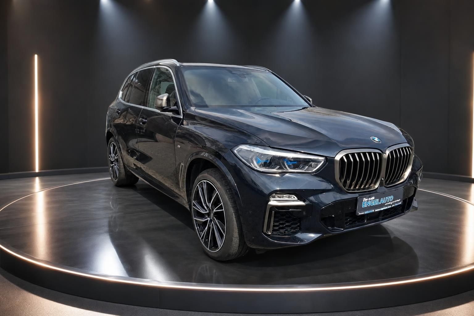 BMW X5 SUV dunkelblau metallic Frontansicht schräg in modernem Showroom mit Spotbeleuchtung