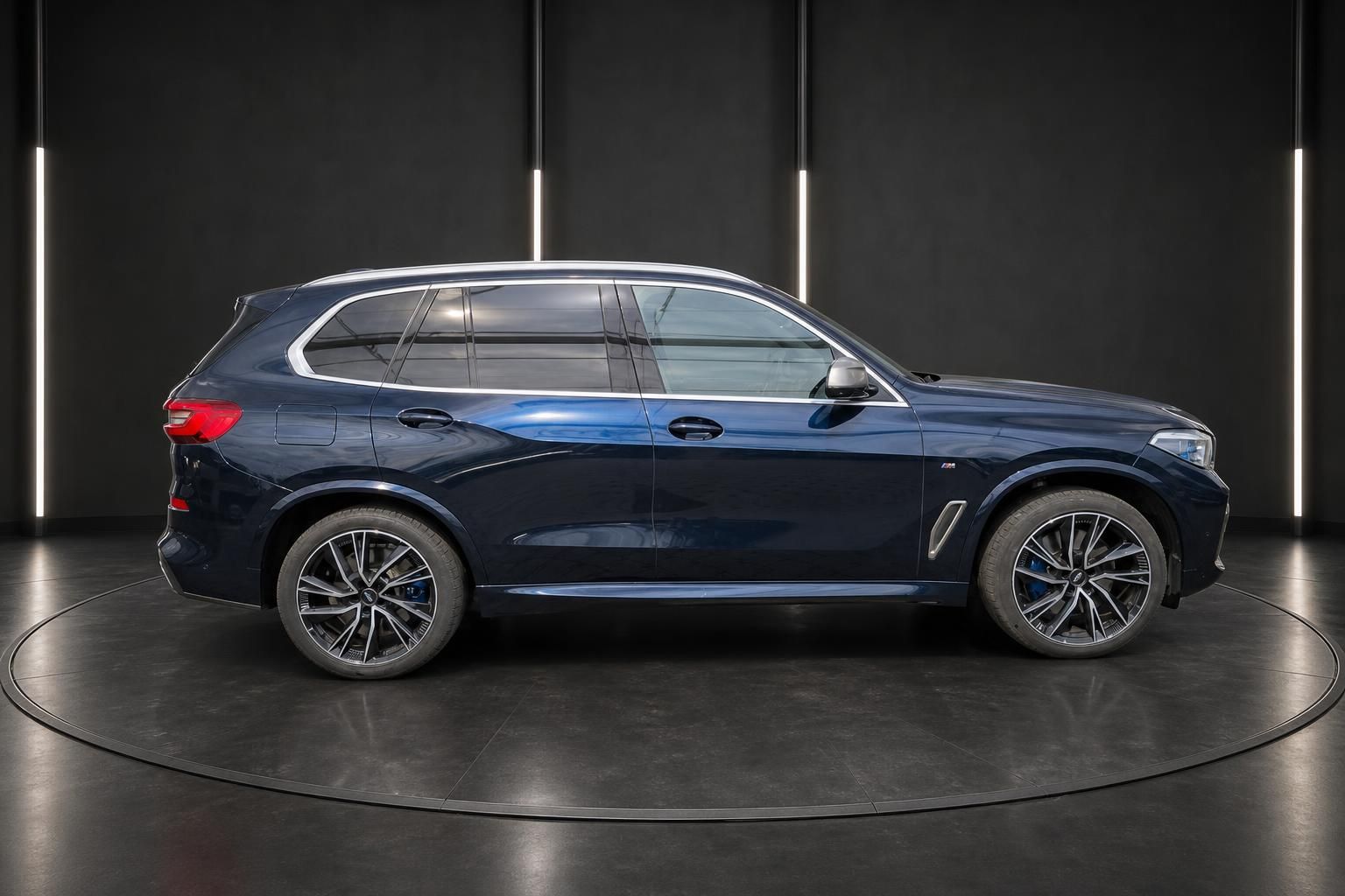 BMW X5 SUV dunkelblau metallic Seitenansicht rechts mit Sportfelgen in modernem Showroom