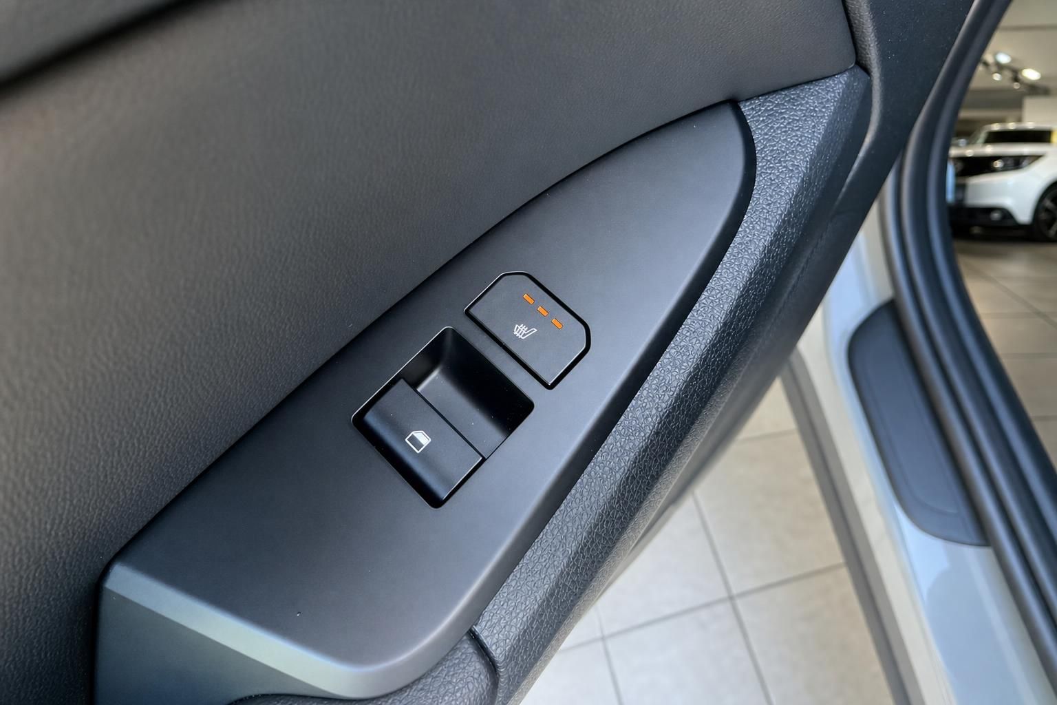 Tuerverkleidung mit Fensterheber und Sitzheizungstaste im Fahrzeuginnenraum