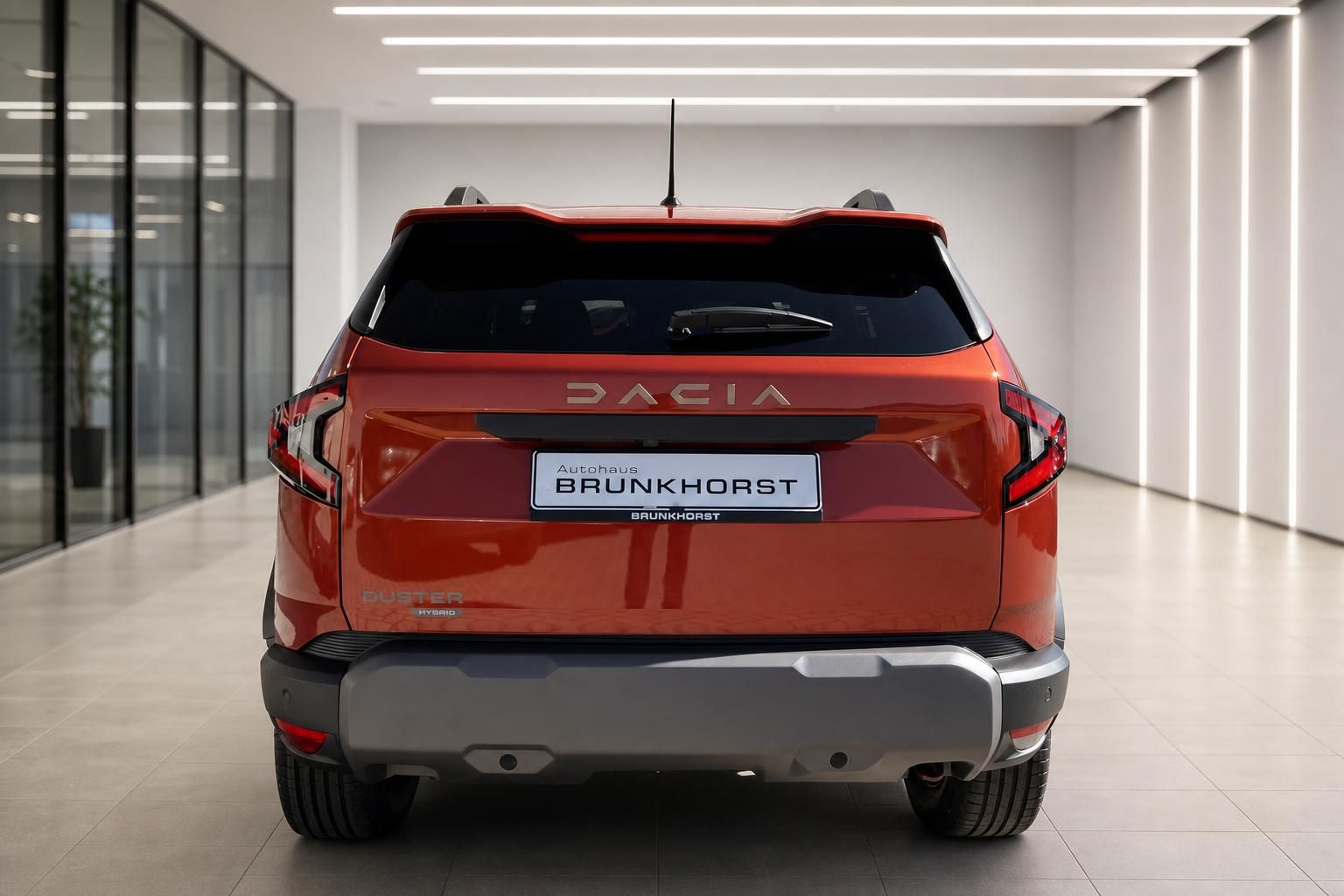 Dacia SUV Heckansicht in orange-rot mit Händlerkennzeichen im Autohaus-Showroom