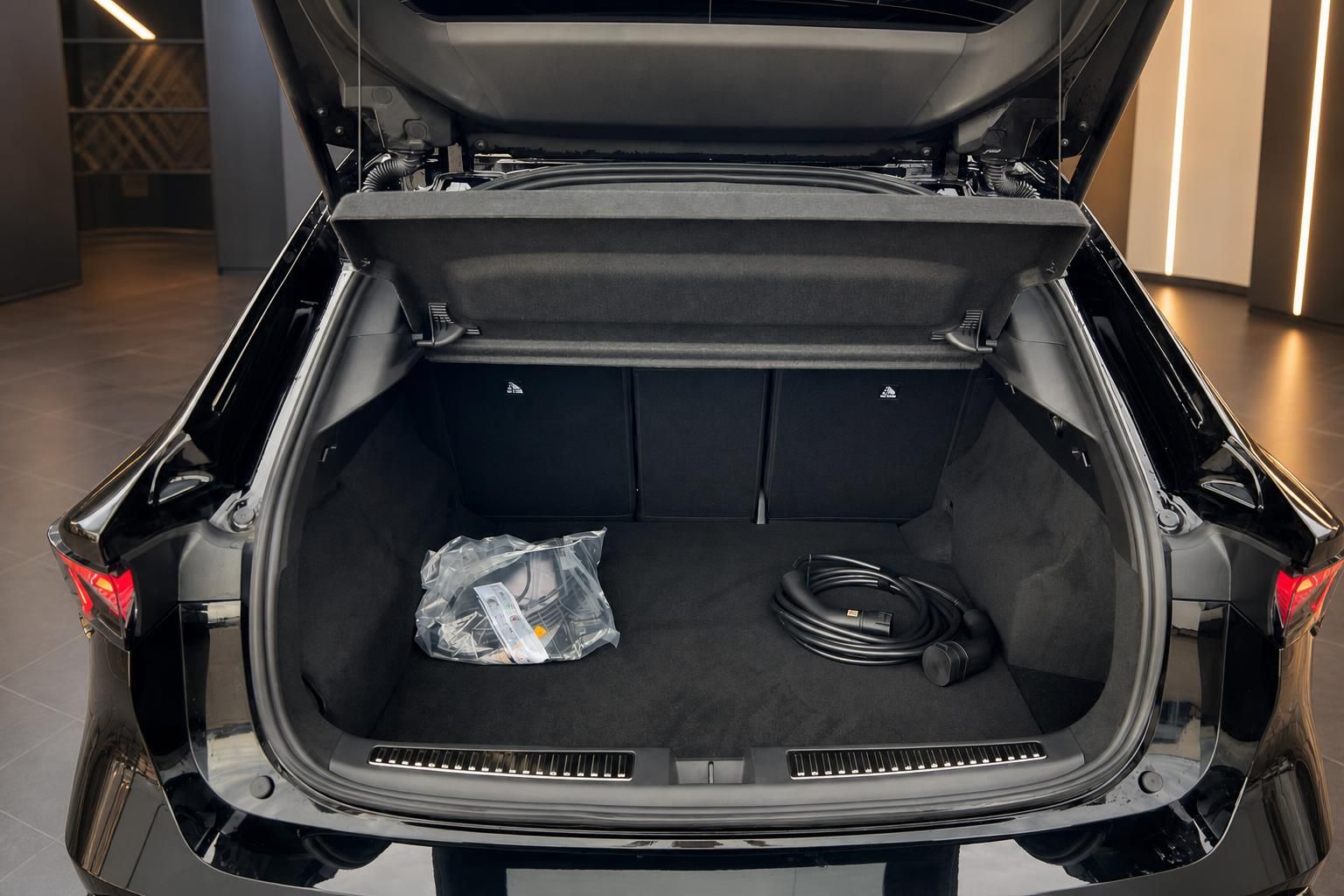 Geöffneter Kofferraum eines schwarzen SUV mit Ladekabel und großem Gepäckraum