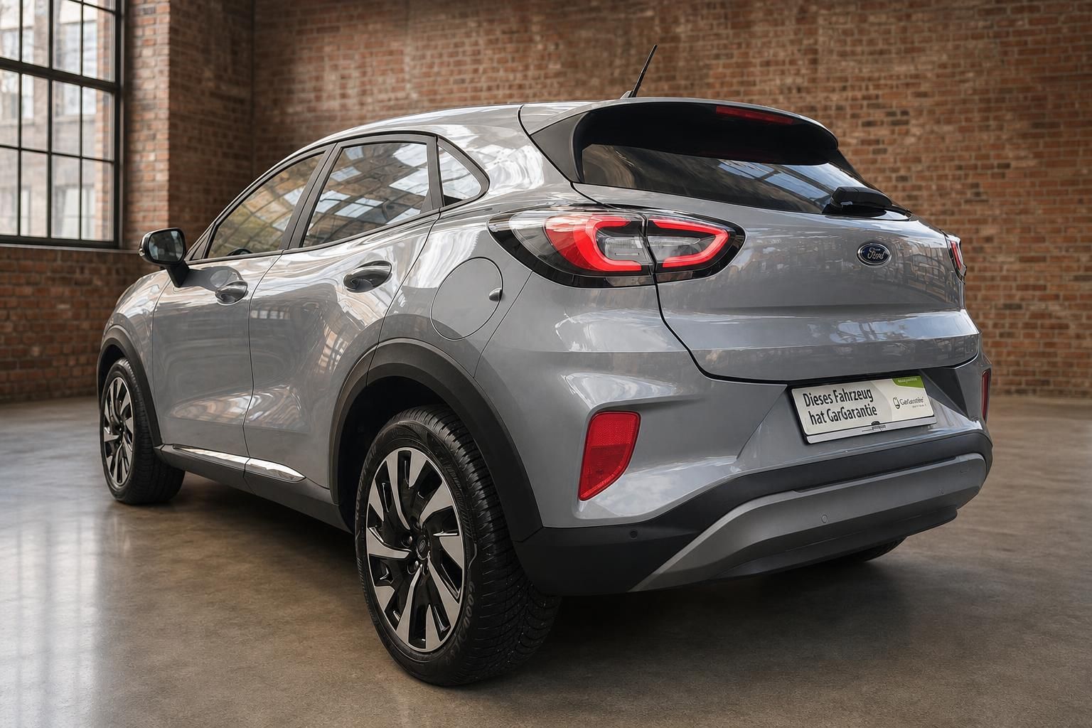 Ford Puma grau Heckansicht schräg rechts – Kompakt-SUV mit Spoiler im Industrieambiente
