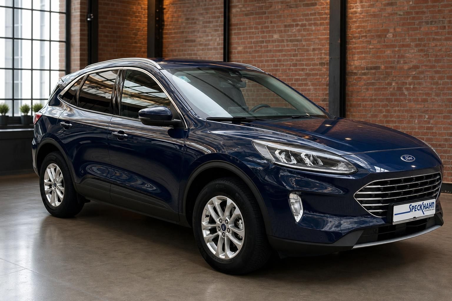 Ford Kuga dunkelblau Frontansicht seitlich vor Backsteinwand