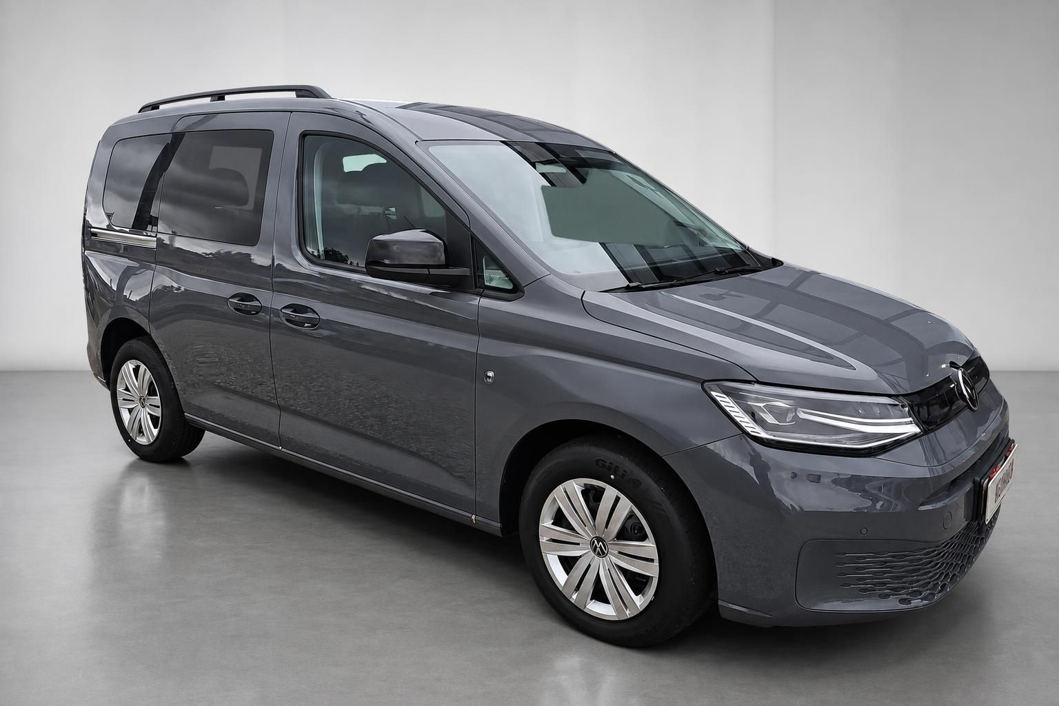 VW Caddy grau Frontansicht schraeg mit LED-Scheinwerfern im Studio